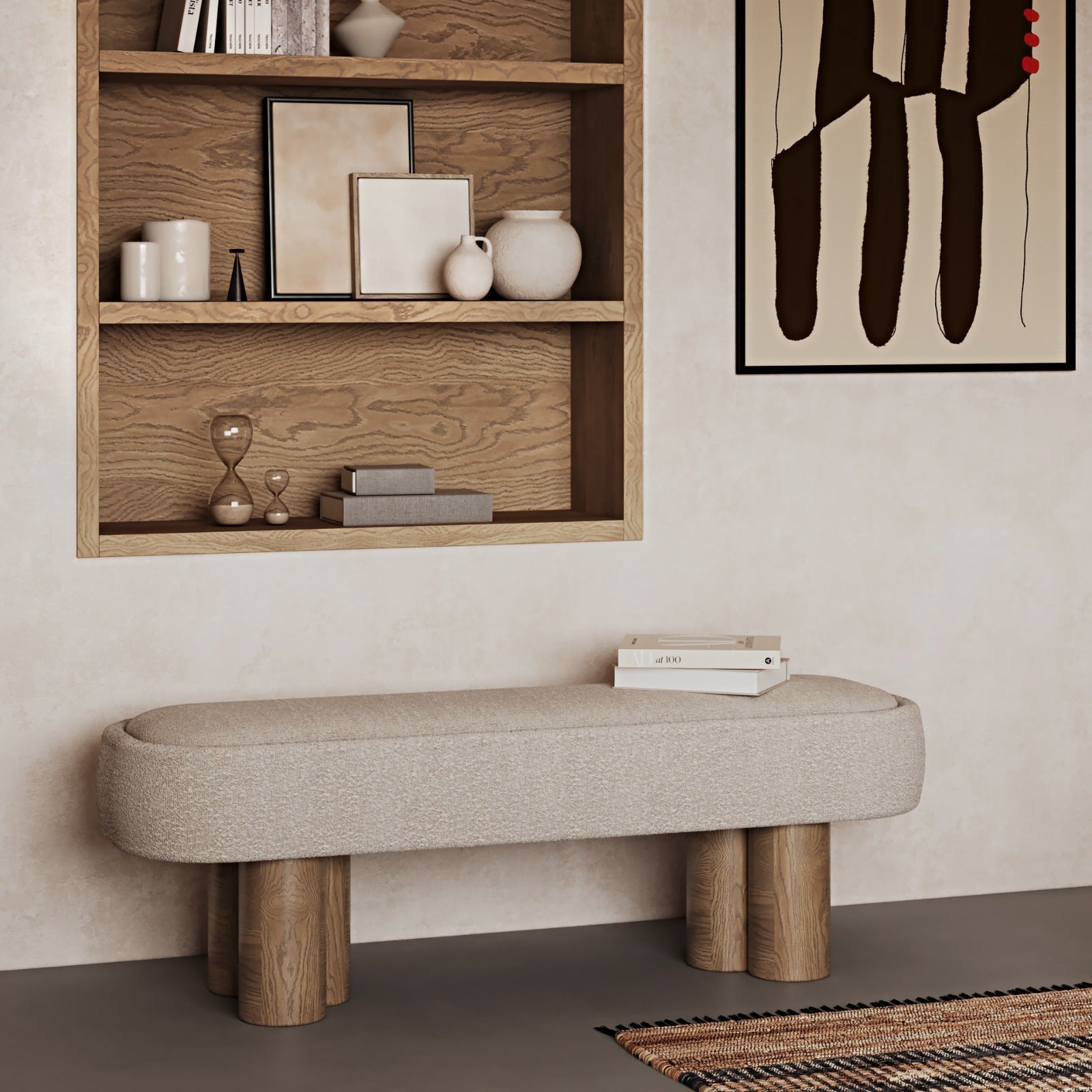 Beige boucle-upholstered bench with a rounded rectangular seat and four natural solid wood cylindrical legs, styled in a coastal-contemporary room beneath built-in oak shelves and abstract wall art with a small stack of books on top.
