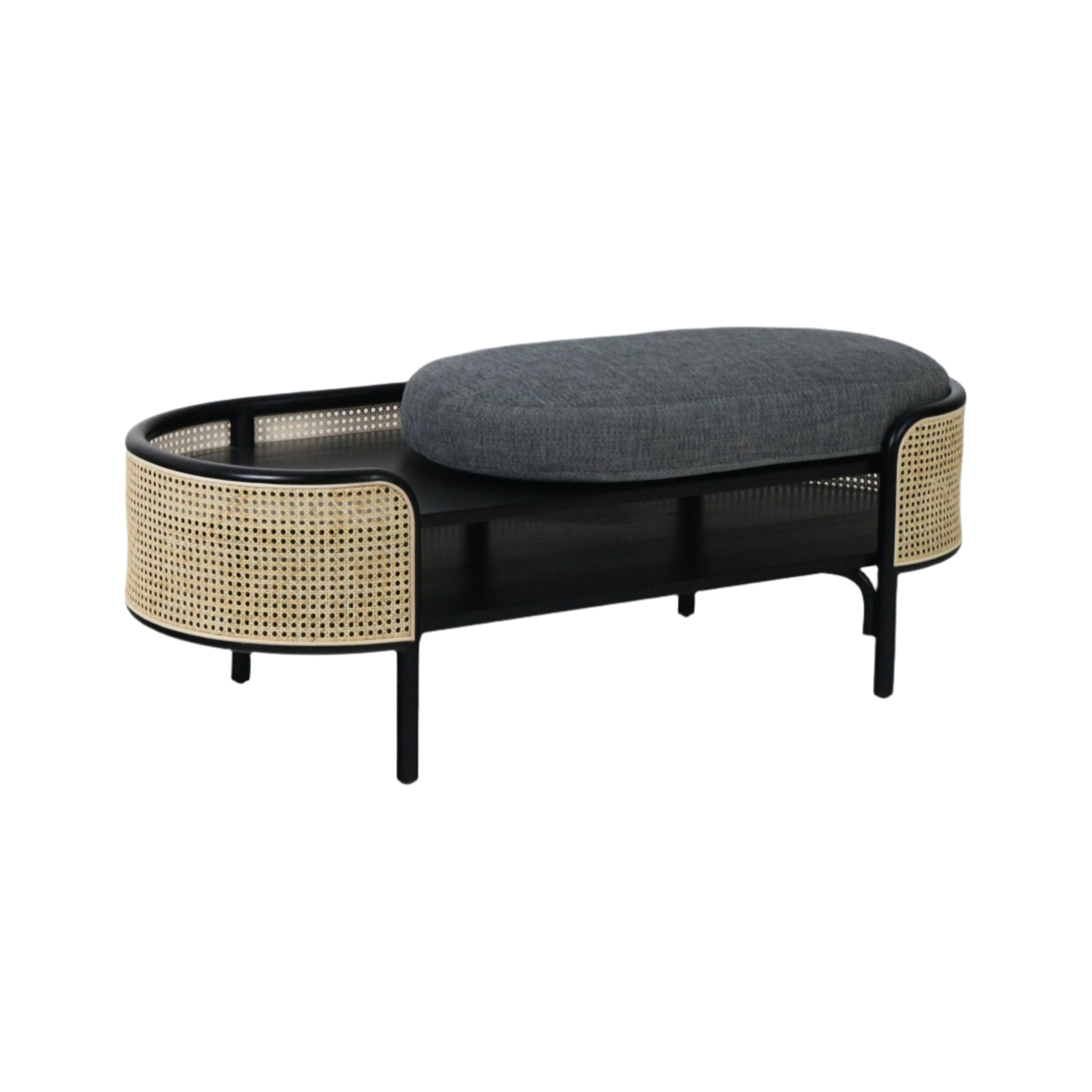 Backless boho bench with a black solid wood frame, natural woven rattan side panels, open lower shelf and a gray upholstered oval seat cushion.