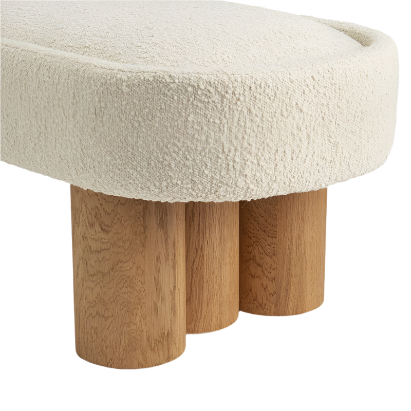 Close-up of a cream boucle upholstered bench seat with a rounded edge, showing textured boucle fabric and three natural solid-wood cylindrical legs.