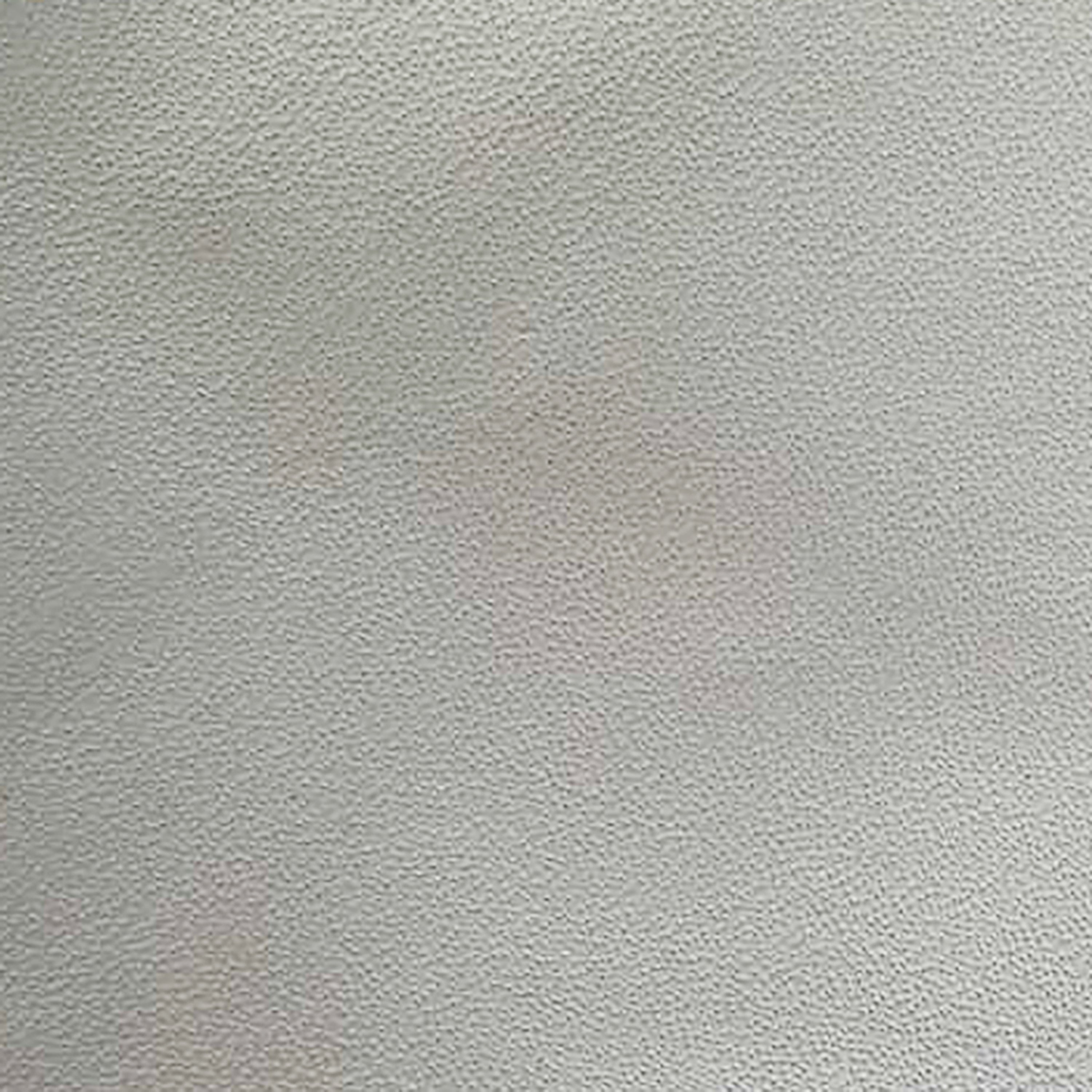 Close-up of cream leather dining chair upholstery showing pebble-grain texture with subtle pinkish discoloration spots on the surface.