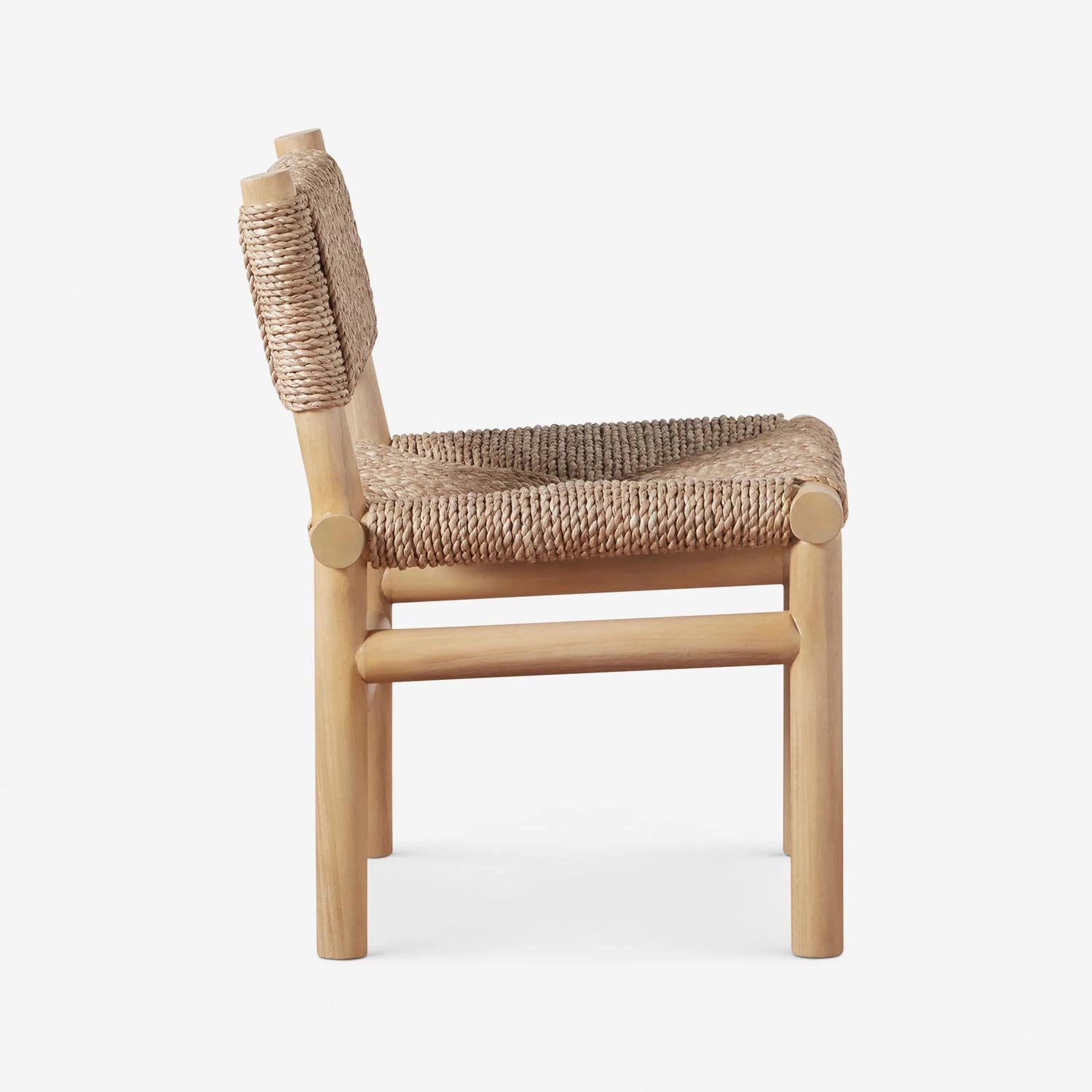 Side profile of an armless outdoor dining chair with a natural teak frame and hand-woven rope seat and low back in a coastal-rustic style.
