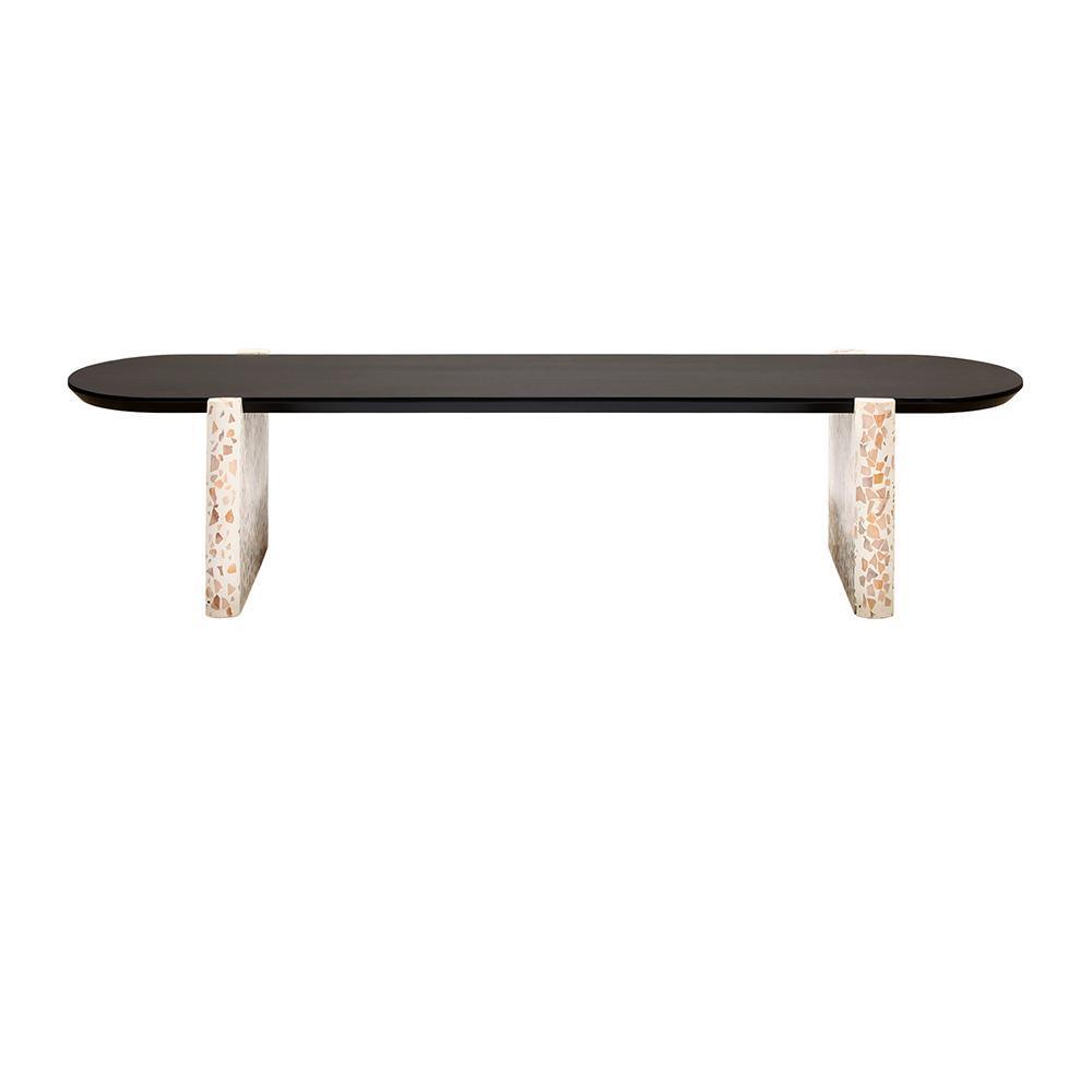 Modern living room coffee table with a long black wooden oval top supported by two white terrazzo slab legs featuring beige and tan stone chips.