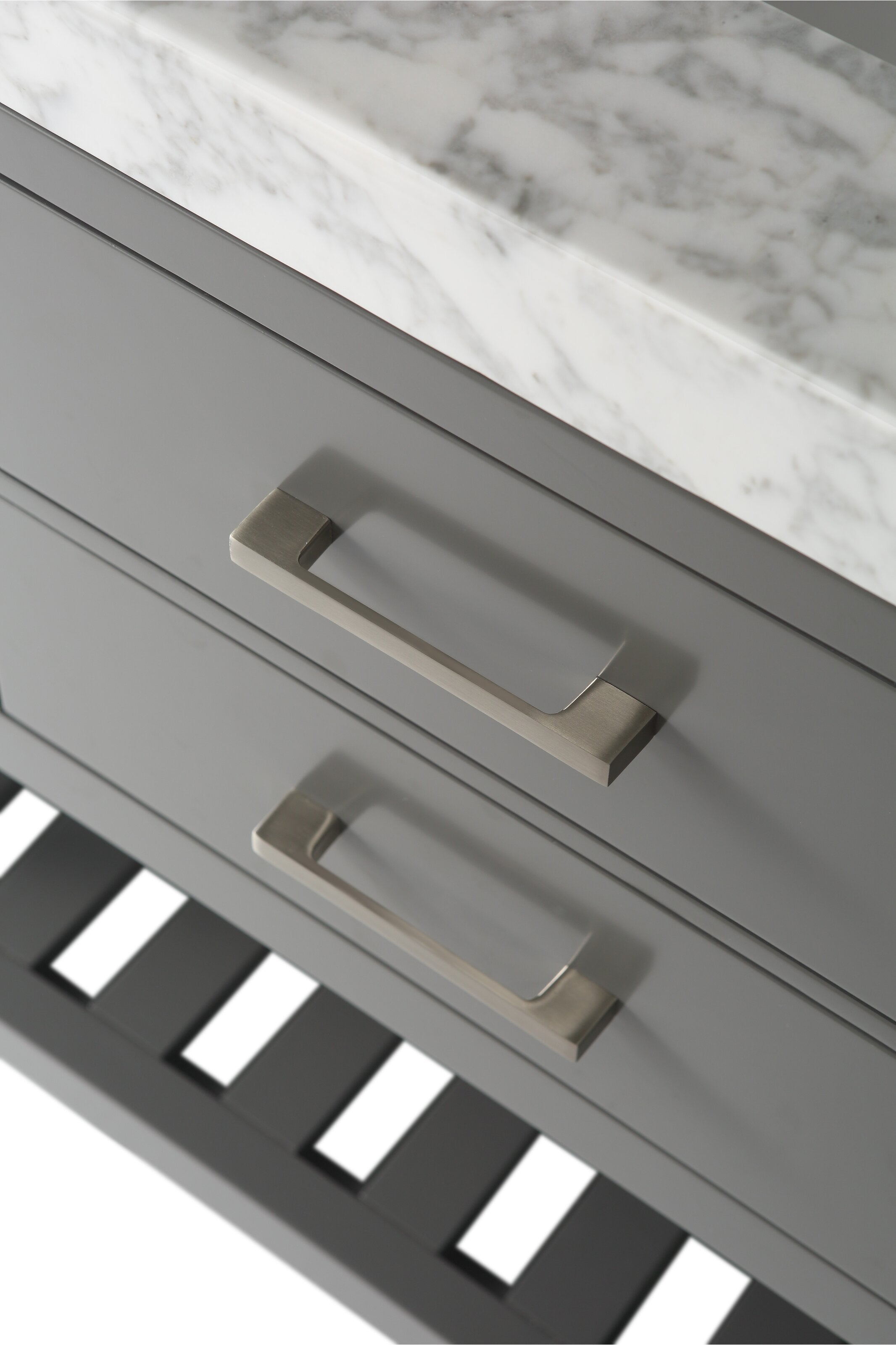 Close-up of a stone-top solid wood bathroom vanity showing stone-gray drawer fronts with brushed-gold rectangular handles, the marble-patterned stone countertop edge and a slatted lower shelf in a modern style.