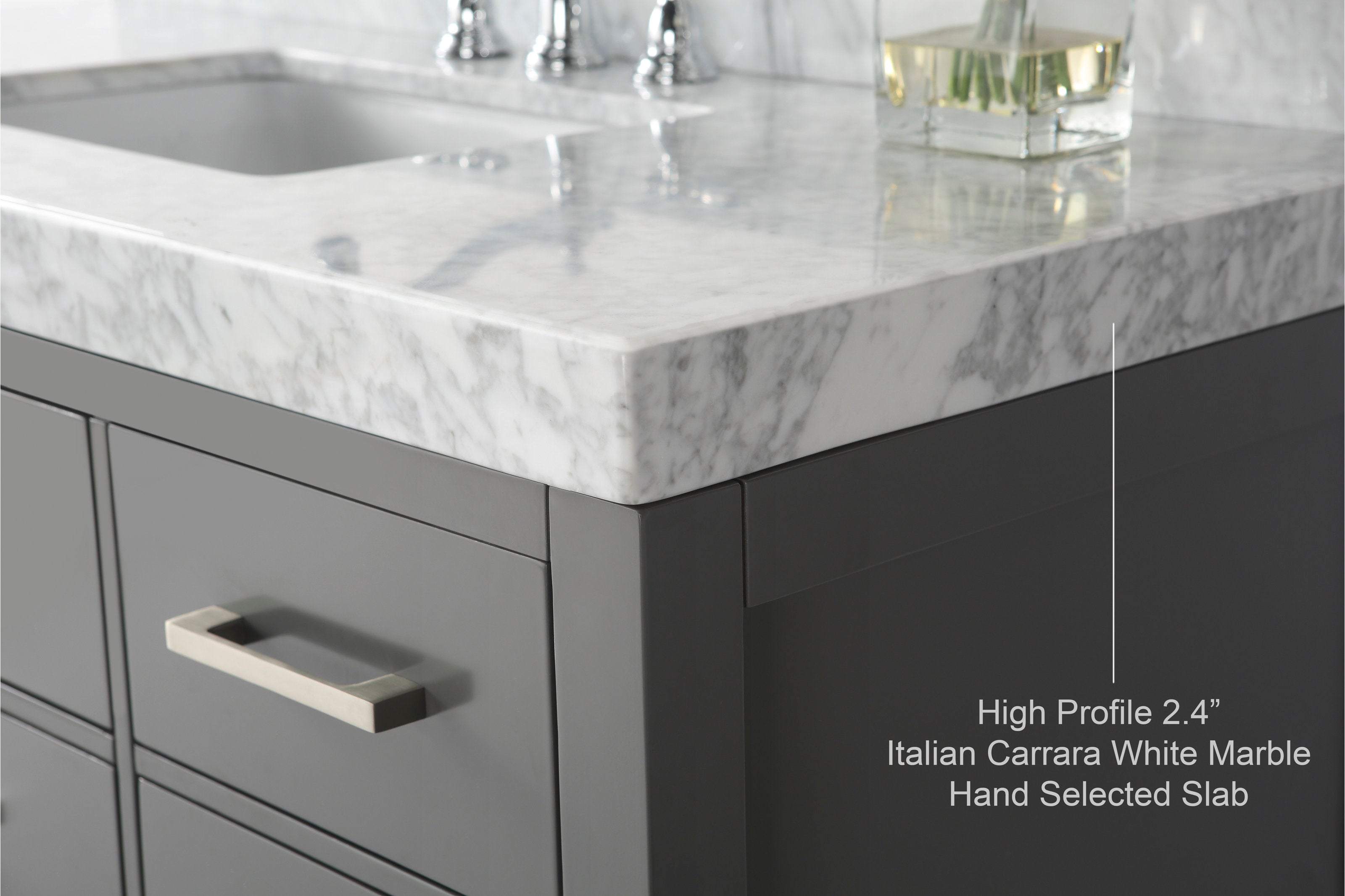 Close-up of a 2.4-inch high-profile Italian Carrara white marble top with grey veining on a stone-gray solid wood modern vanity, showing the undermount sink edge and a brushed-metal rectangular drawer pull.