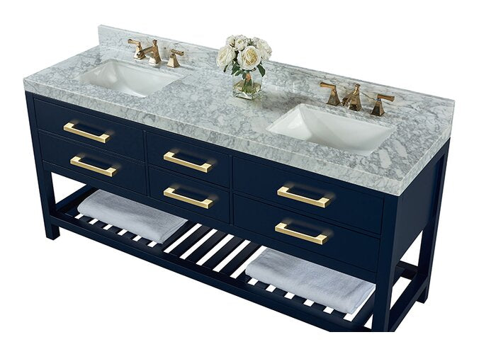 72-inch freestanding solid wood double-sink vanity with a stone marble top, two white ceramic undermount sinks, navy painted base, brass handles and faucets, and an open slatted lower shelf with folded towels and a vase of flowers.