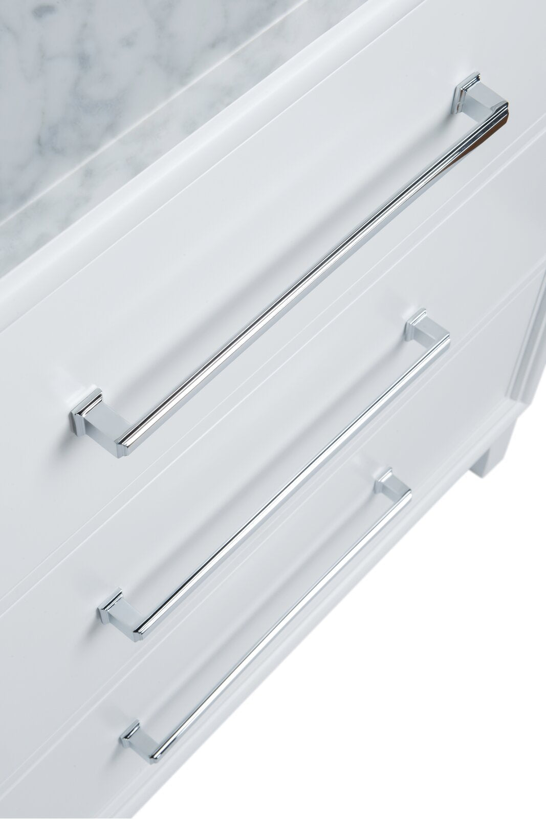 Close-up of three chrome bar handles mounted on white solid wood vanity drawers with a stone marble top edge visible, showing a modern bathroom vanity hardware detail.