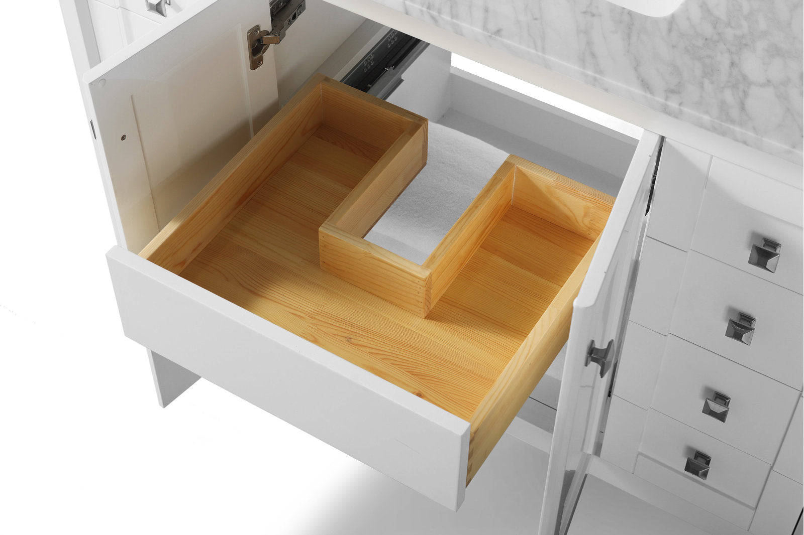 Top-down view of an open white modern bathroom vanity drawer showing a natural solid-wood interior with a U-shaped cutout for plumbing beneath a stone marble countertop and ceramic sink.
