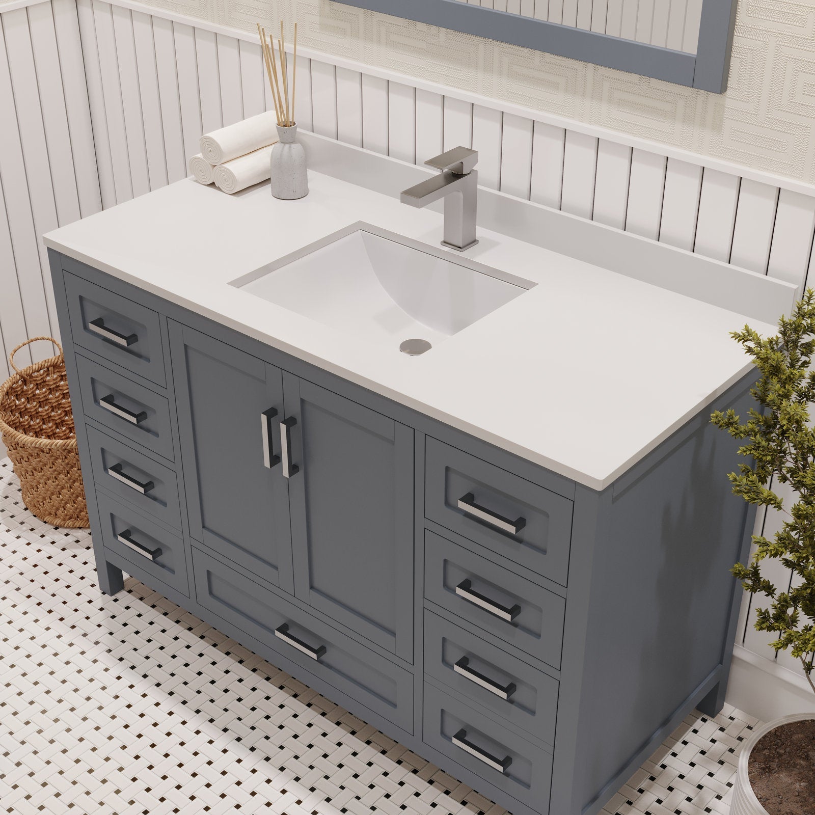 Freestanding modern gray solid wood bathroom vanity with white stone countertop and integrated rectangular sink, brushed-nickel faucet, multiple drawers and center cabinet shown on a mosaic tile floor.