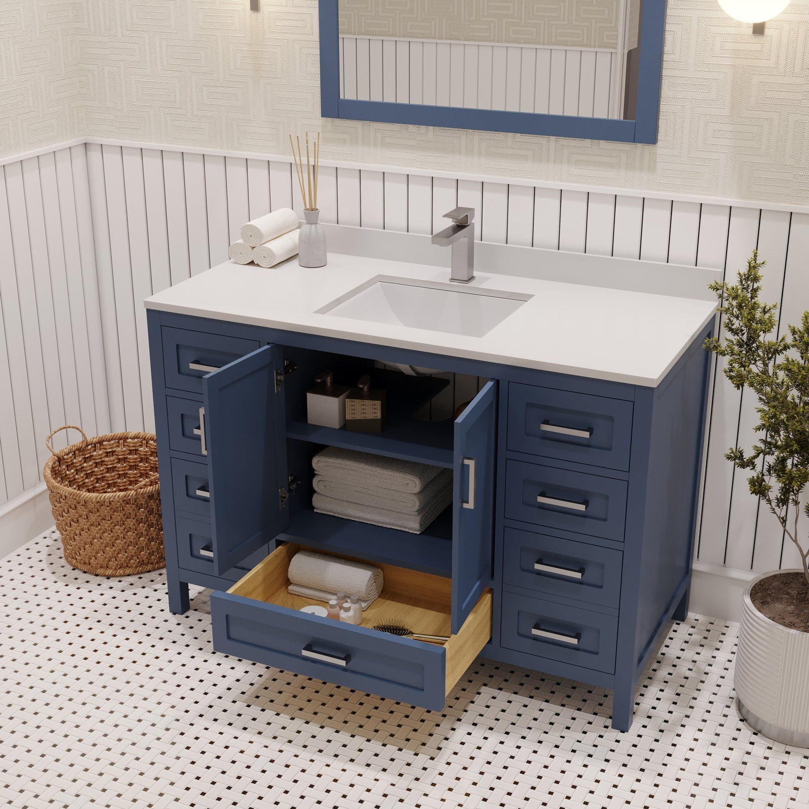 Freestanding modern navy solid-wood bathroom vanity with a white stone countertop, integrated rectangular ceramic sink and single chrome faucet; open cabinet doors and a pulled drawer reveal shelves with folded towels and bath accessories.