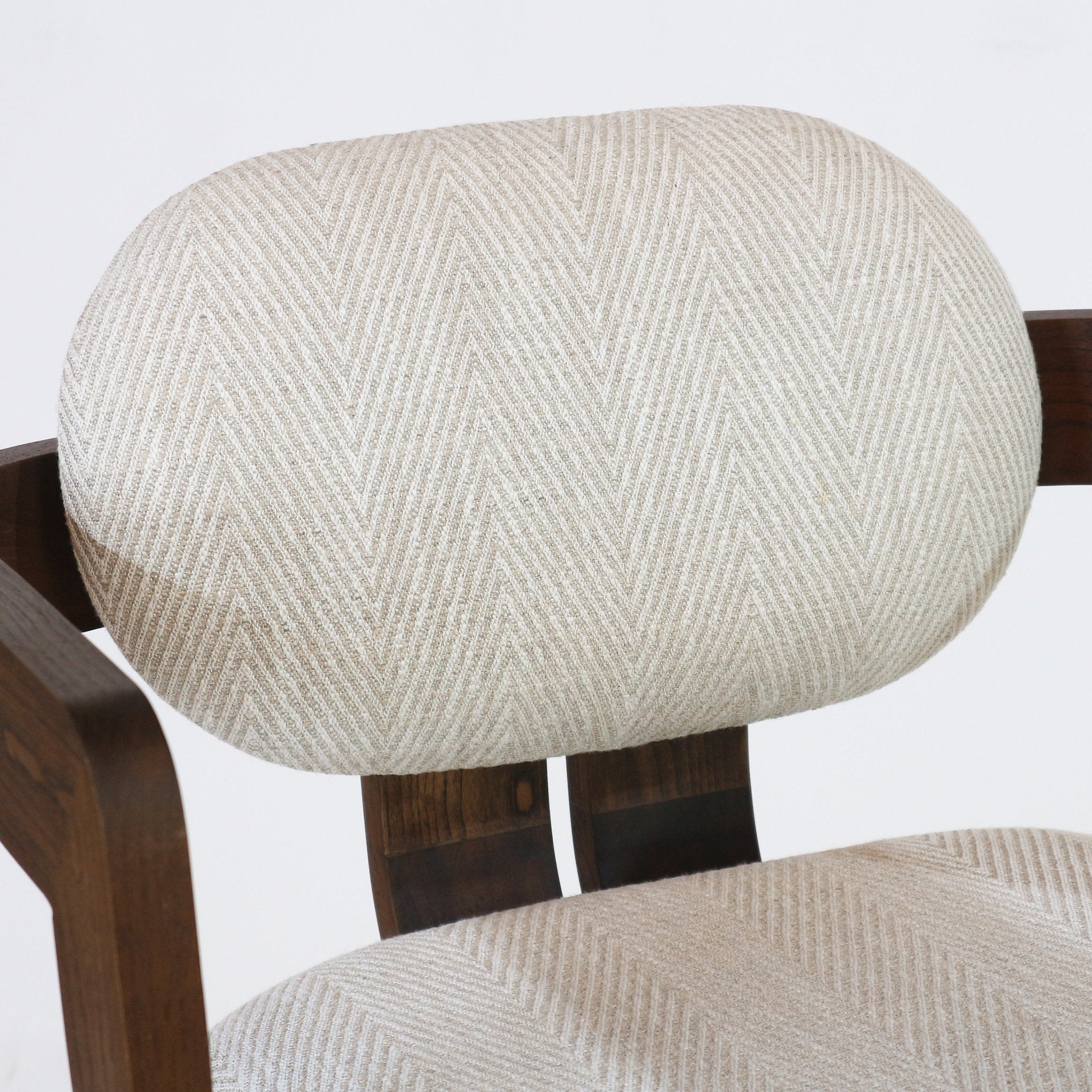 Close-up of a beige herringbone fabric upholstered oval backrest and matching cushioned seat attached to a dark natural wood frame of a modern bar stool.