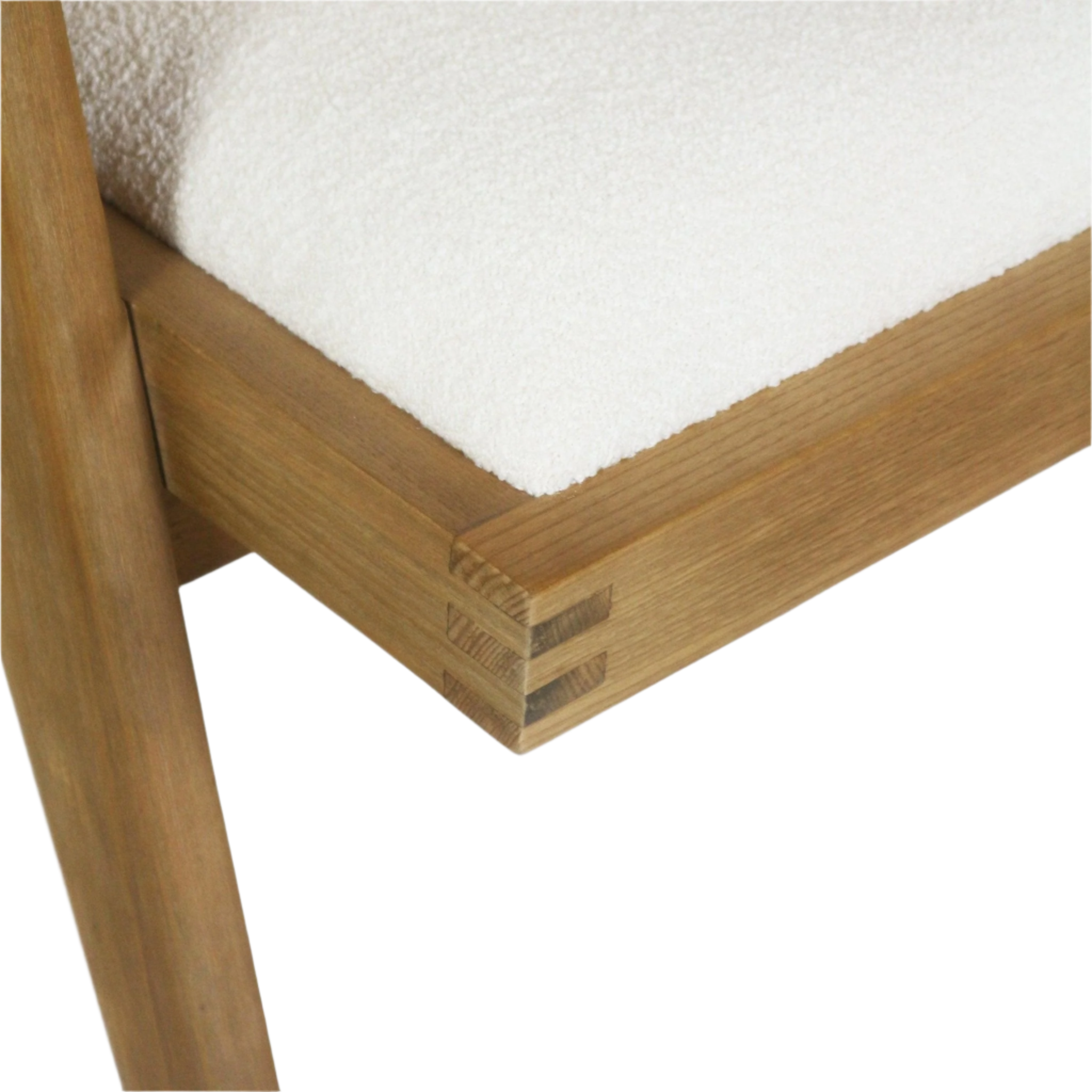 Close-up of a natural blonde wood chair corner showing exposed finger joints and a white boucle upholstered seat cushion.