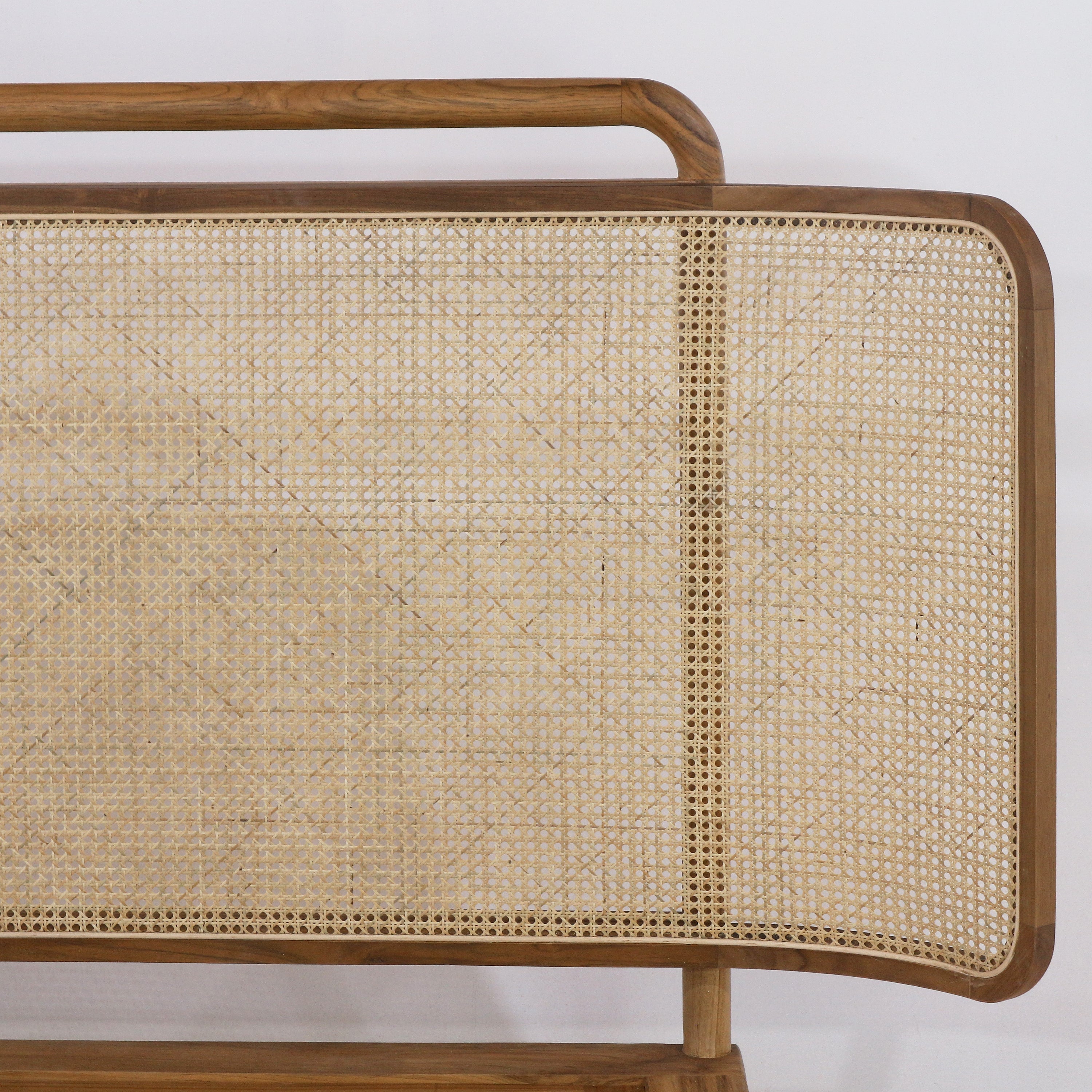 Close-up of a teak wood headboard showing natural rattan/cane weave panel, rounded teak frame and slim top rail in a warm teak finish.
