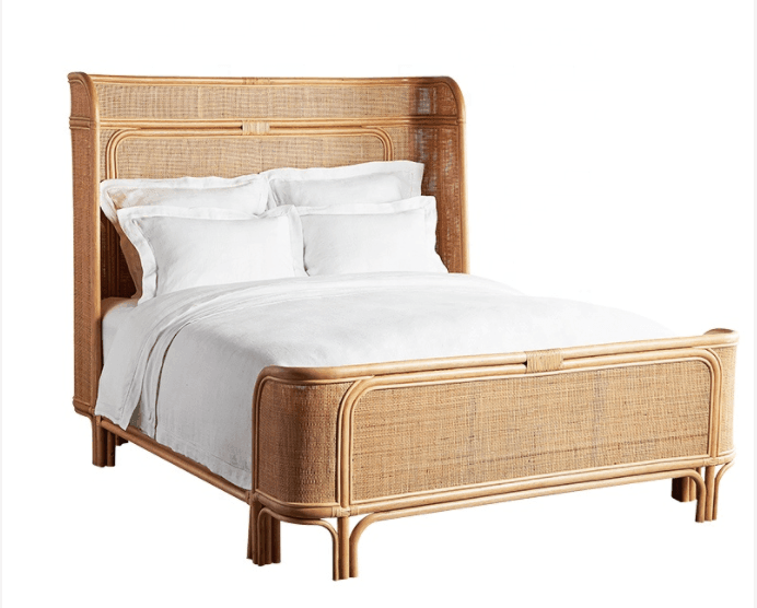 Natural teak and rattan platform bed with a tall woven headboard and matching woven footboard, shown dressed in white bedding in a boho-inspired natural wood finish.