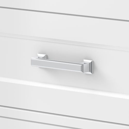 Close-up of a polished chrome rectangular drawer pull mounted on a white solid-wood bathroom vanity drawer front with recessed horizontal grooves, showing modern hardware detail and clean contemporary finish.