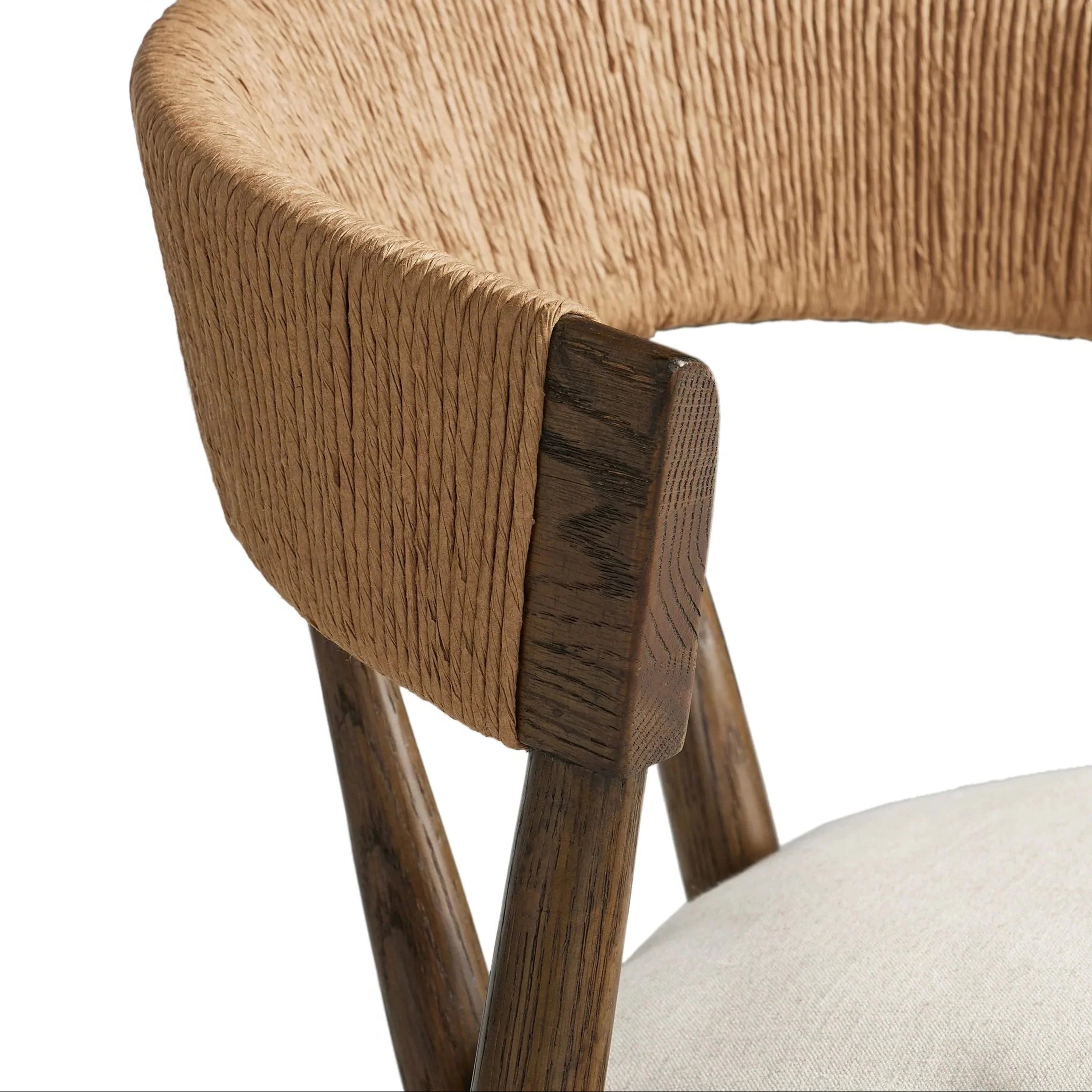 Close-up of a natural tan rope-wrapped C-shaped backrest on a dark stained wood frame with a light beige upholstered seat cushion visible at the corner.