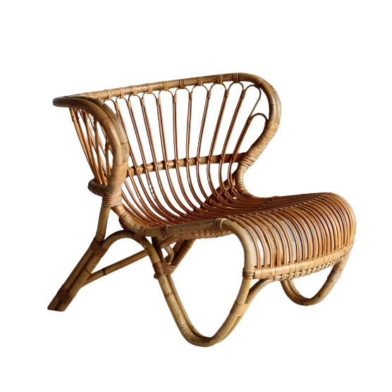 Light natural rattan lounge chair with a low sculptural frame, curved slatted back and woven open seat — an armless boho accent for living rooms or patios.