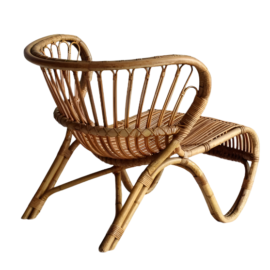 Natural rattan lounge chair with a curved open-weave backrest, low woven seat and looped angled legs in a boho-Scandinavian style.