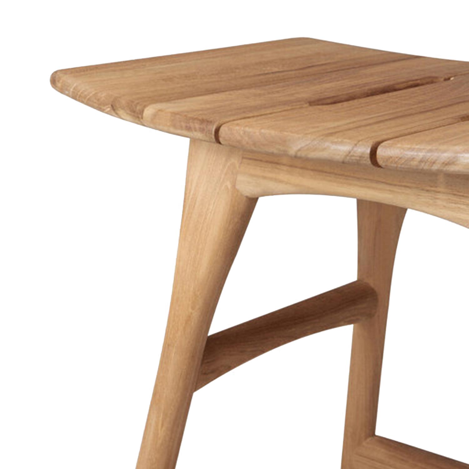 Close-up of a natural teak backless shower stool showing the slatted seat corner, rounded edge, tapered leg and curved stretcher in a contemporary coastal style.