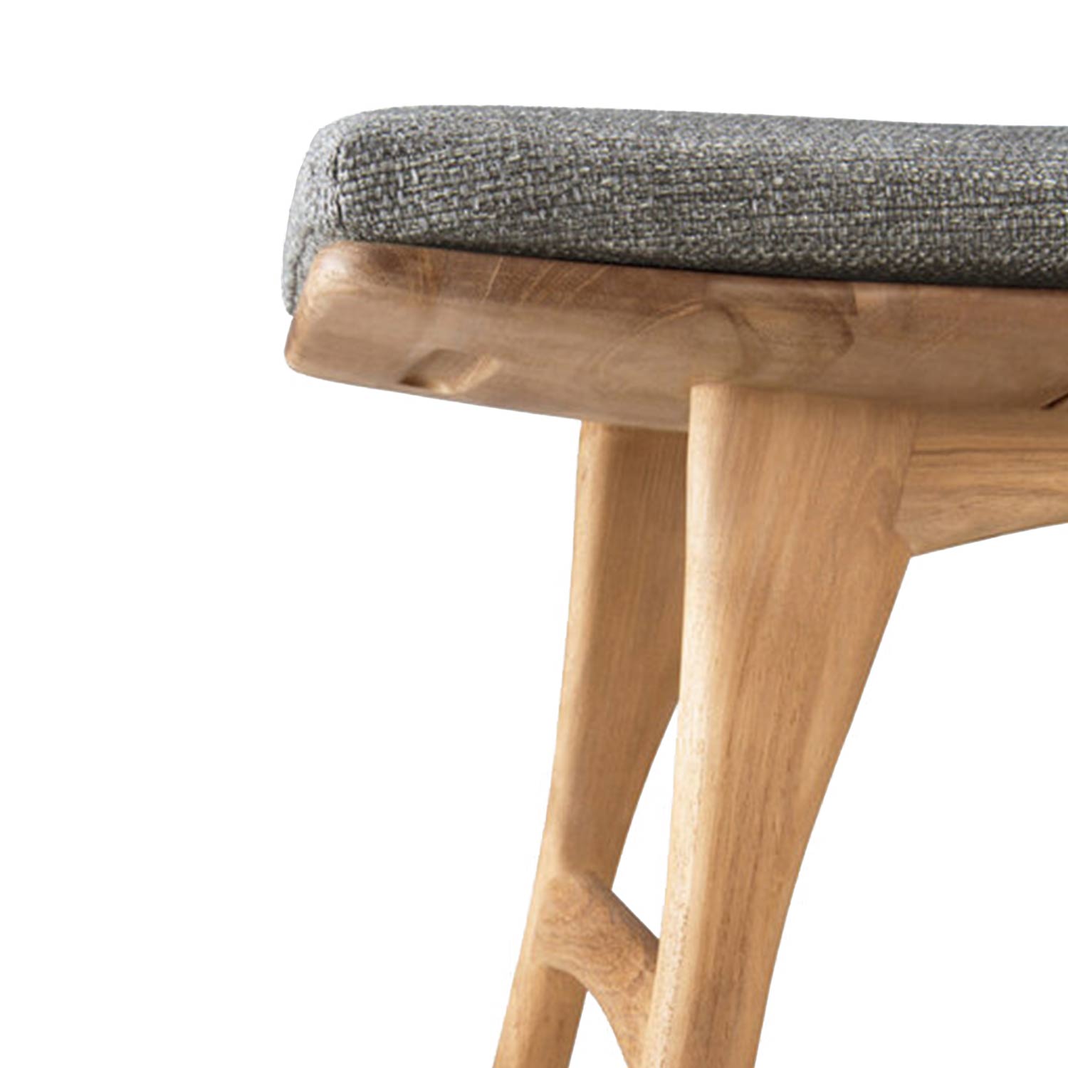 Close-up of a teak shower stool seat showing a gray textured upholstered cushion atop a natural teak wood frame with tapered carved legs and visible wood grain.