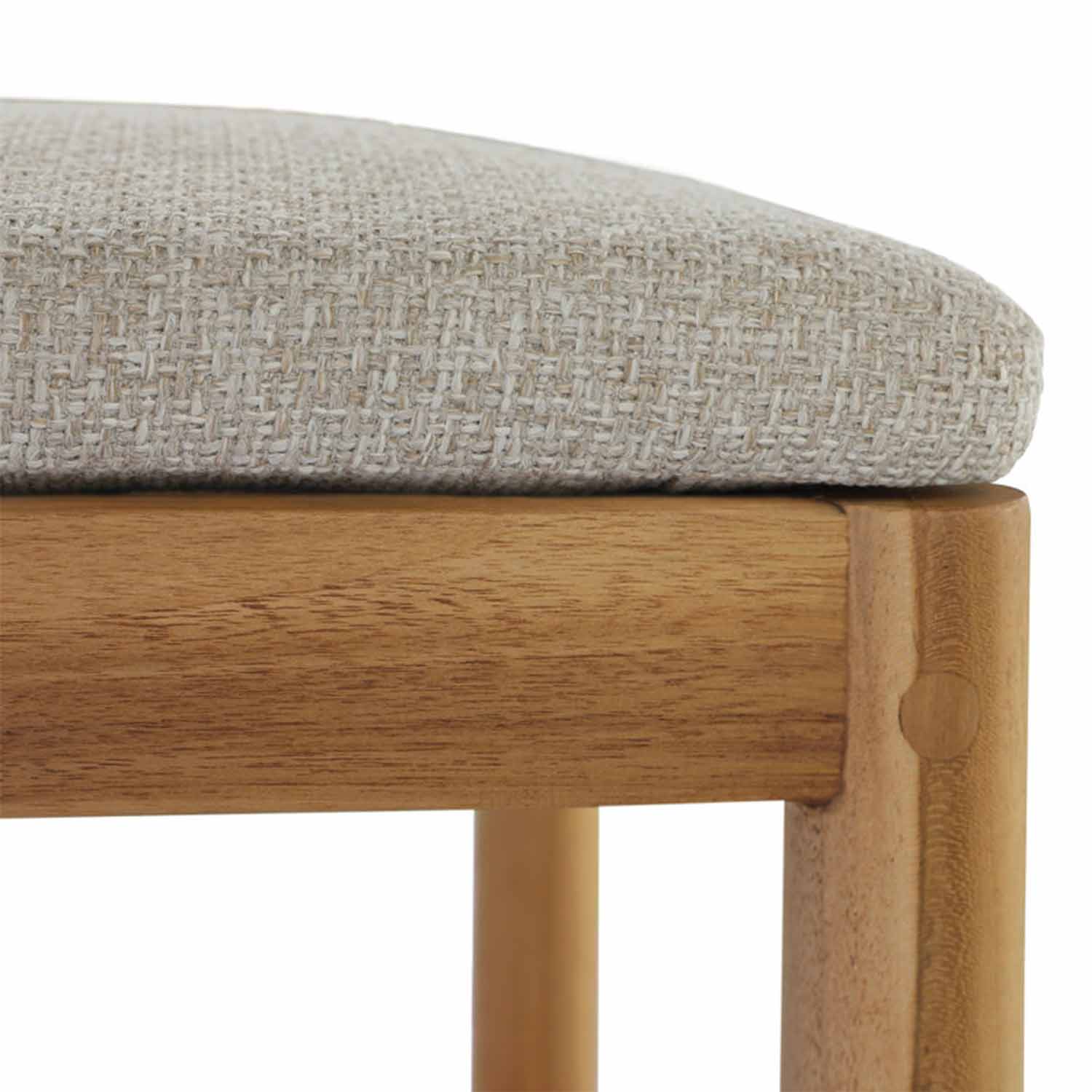 Close-up of an armless teak outdoor bar stool showing a neutral woven upholstered seat cushion resting on a solid teak frame with visible dowel joinery and rounded leg.