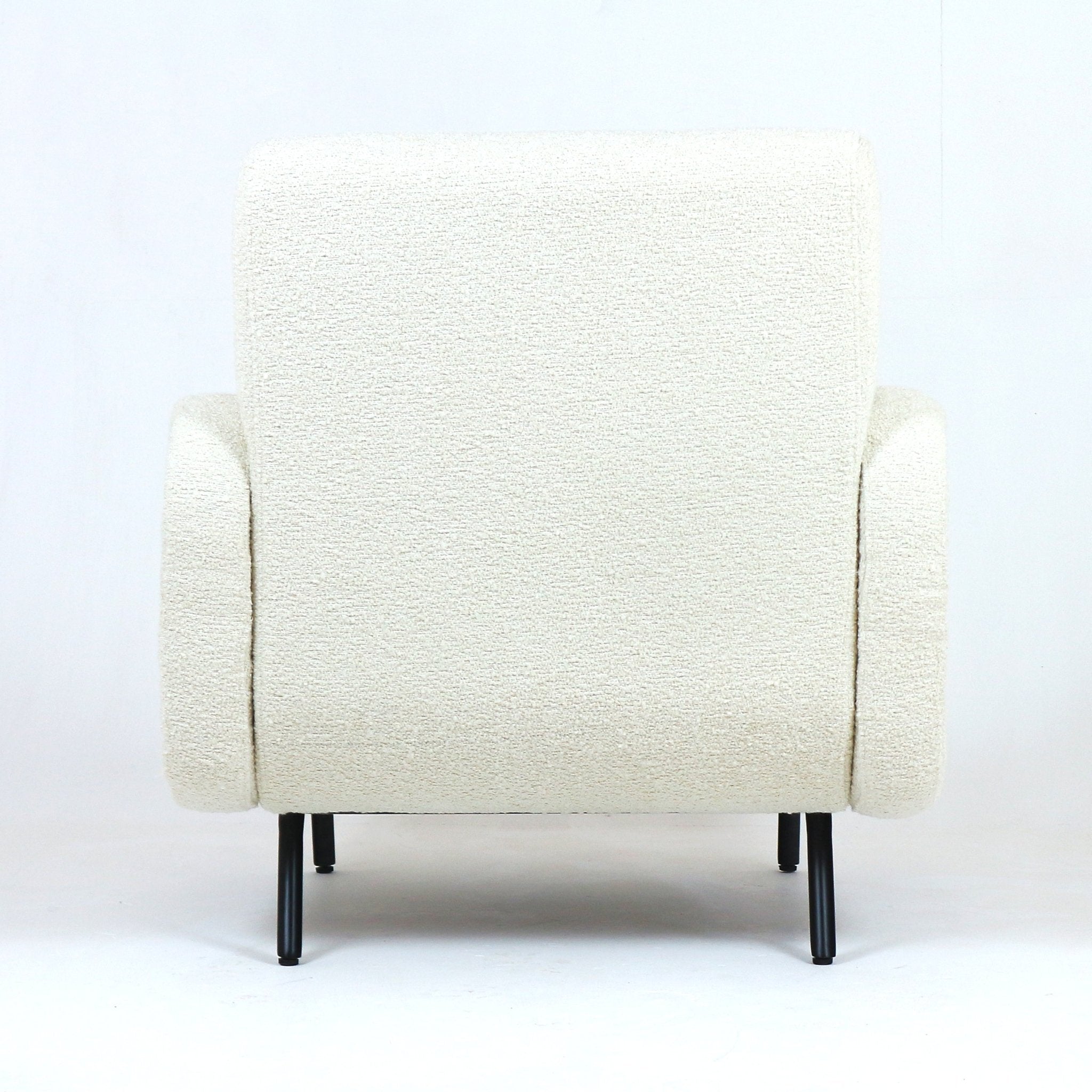 Back view of a white boucle upholstered armchair with rounded arms, low back and slim black metal legs on a plain white backdrop.