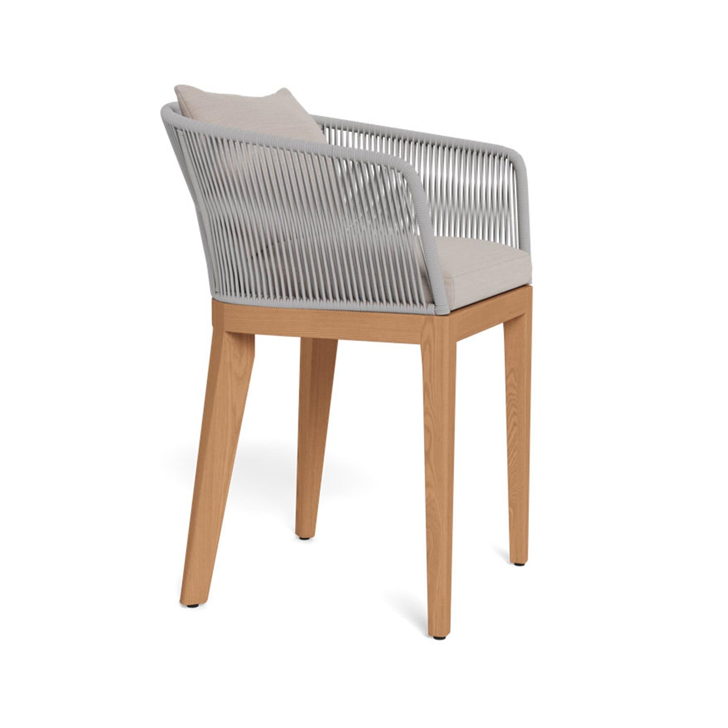 Outdoor bar stool with teak frame and tapered legs, light-gray upholstered seat and back pillow, and a woven gray rope-wrapped back and arms in a coastal, contemporary style.