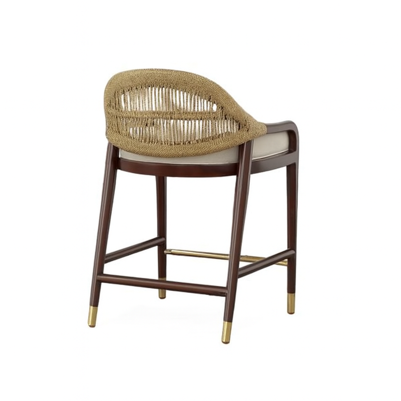 Rear three-quarter view of a teak-framed counter stool with a natural rope-woven curved back, beige upholstered seat cushion, dark teak legs and brass foot caps plus a brass footrest.
