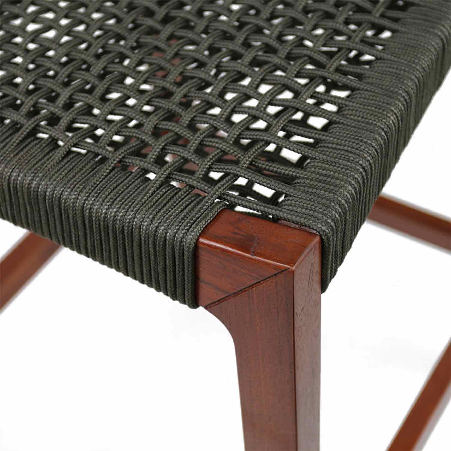Close-up of an outdoor teak bar stool corner showing dark olive-gray woven rope seat tightly wrapped and interlaced over a solid teak frame and tapered leg.