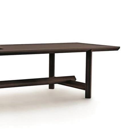 Cropped view of a mid-century modern teak dining table showing the right end of the rectangular tabletop, vertical legs and angled stretcher in a warm natural teak solid wood finish on a white background.