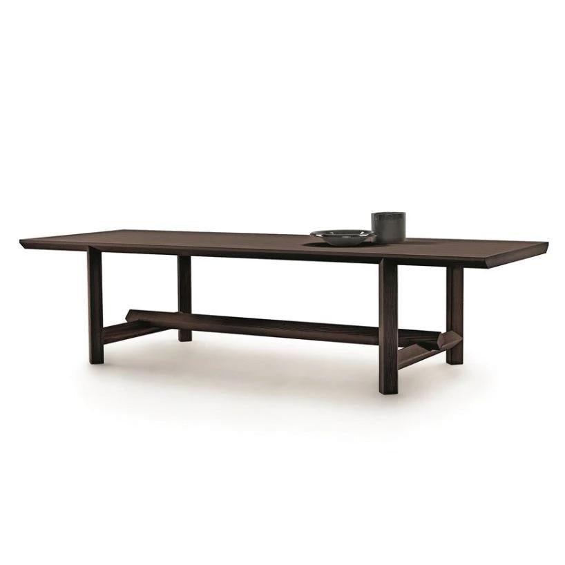 Long rectangular teak dining table in a dark natural wood finish with squared legs and a central stretcher, styled in mid-century modern design and staged with a ceramic bowl and small vase on the tabletop.