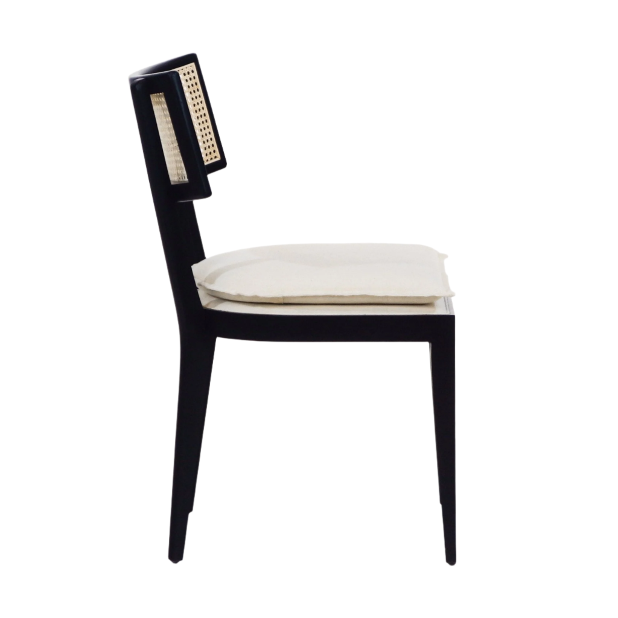 Side view of an armless black solid wood dining chair with a natural rattan cane backrest and cream upholstered seat cushion, slim tapered legs and a mid-century modern, boho-inspired silhouette.