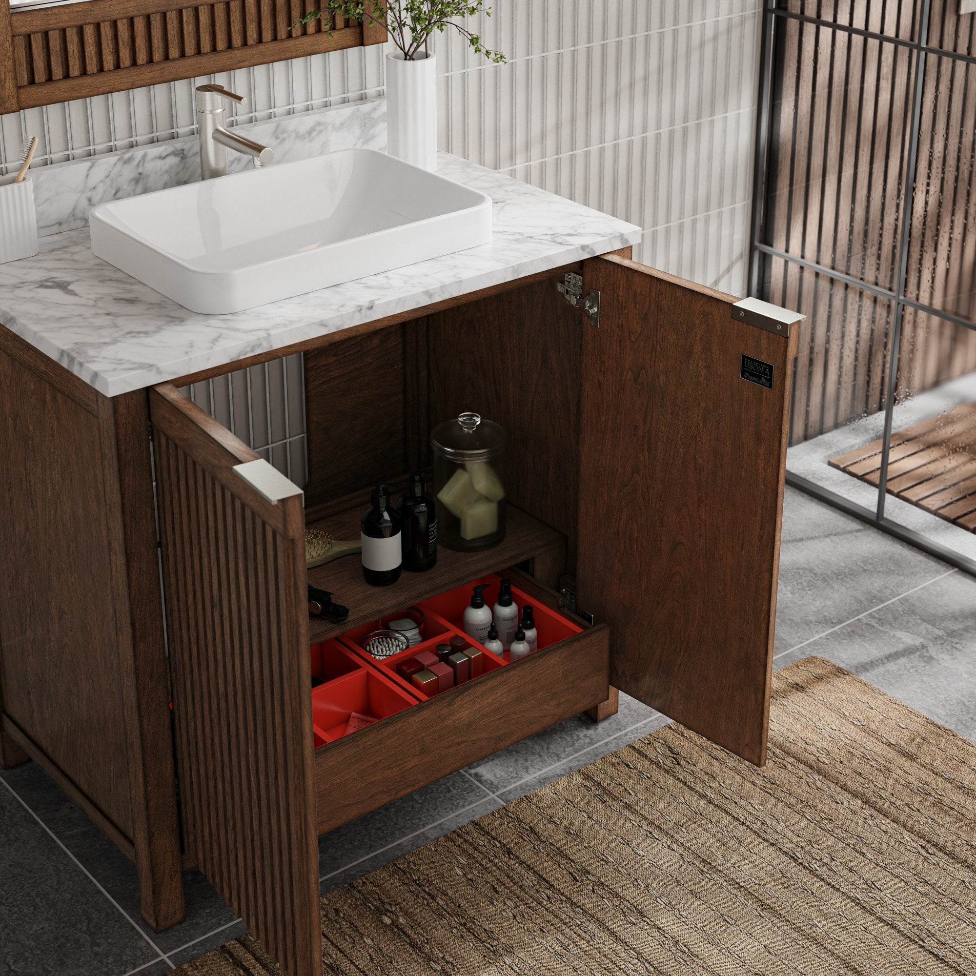 Modern solid-wood bathroom vanity with fluted doors and stone-look marble top, paired with a white rectangular vessel sink; one cabinet door open to reveal interior shelf and red organizer tray holding bottles and toiletries.