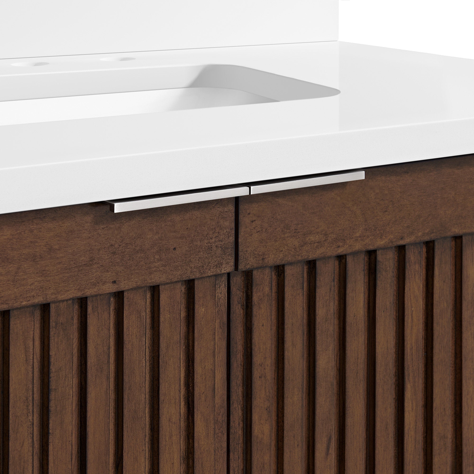 Close-up of a modern single-sink bathroom vanity showing a stone top with integrated white basin and slim brushed-metal handles above a brown solid-wood cabinet with vertical fluted panels.