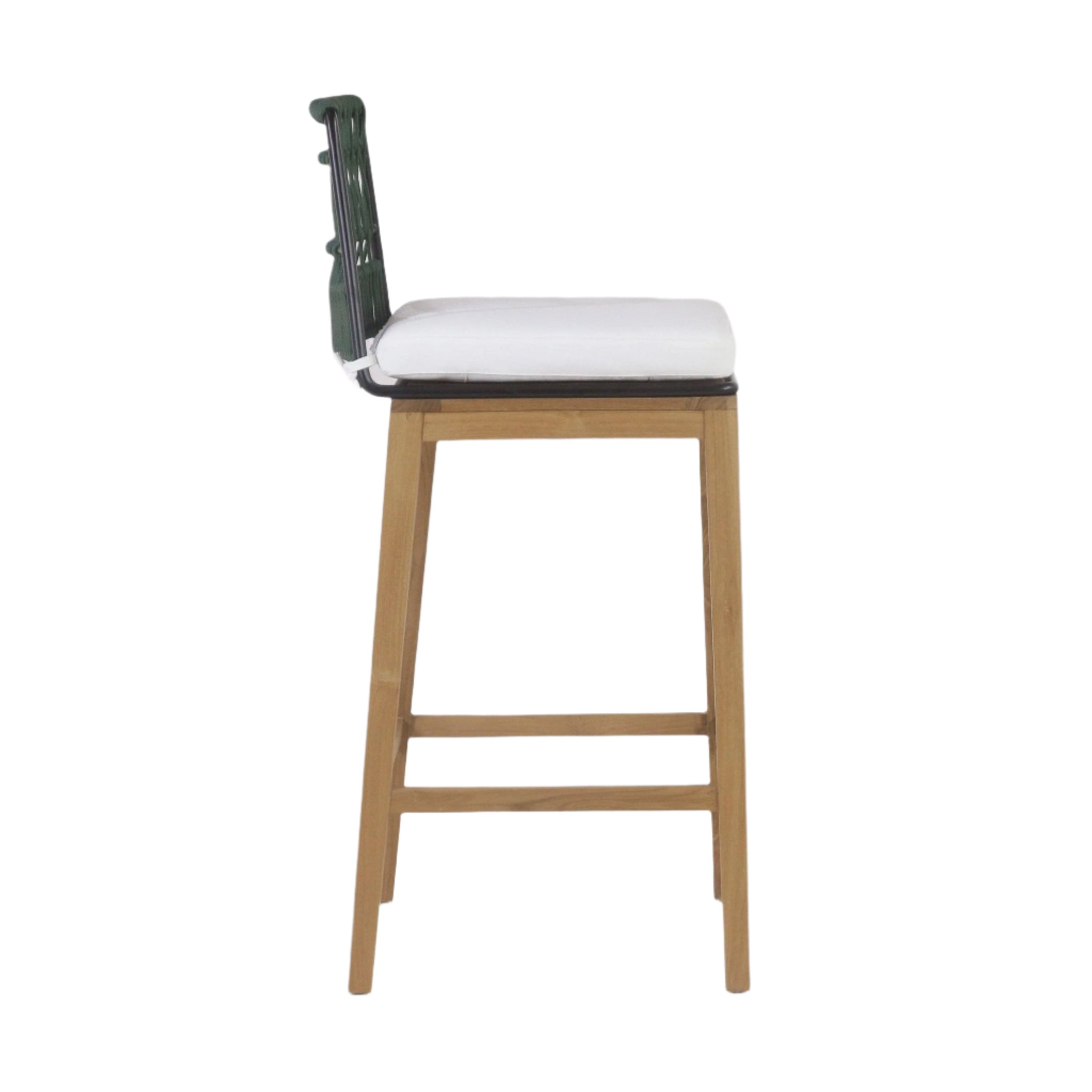 Side view of a mid-century modern outdoor bar stool with teak legs, black metal seat frame, a white fabric cushion and a green woven rope back.