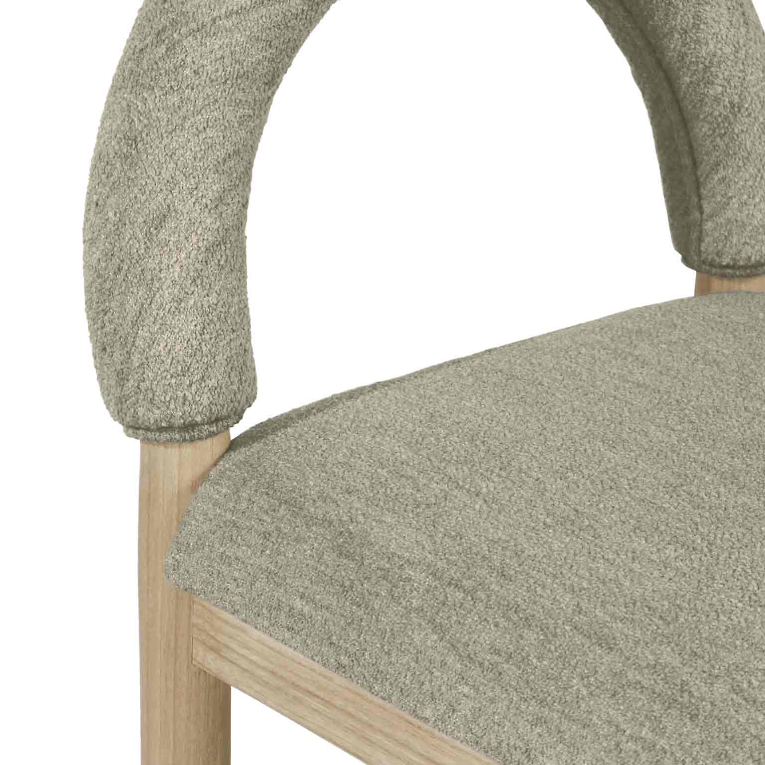 Close-up of a beige-taupe bouclé upholstered stool showing the textured arched back, cushioned seat and natural oak leg detail.