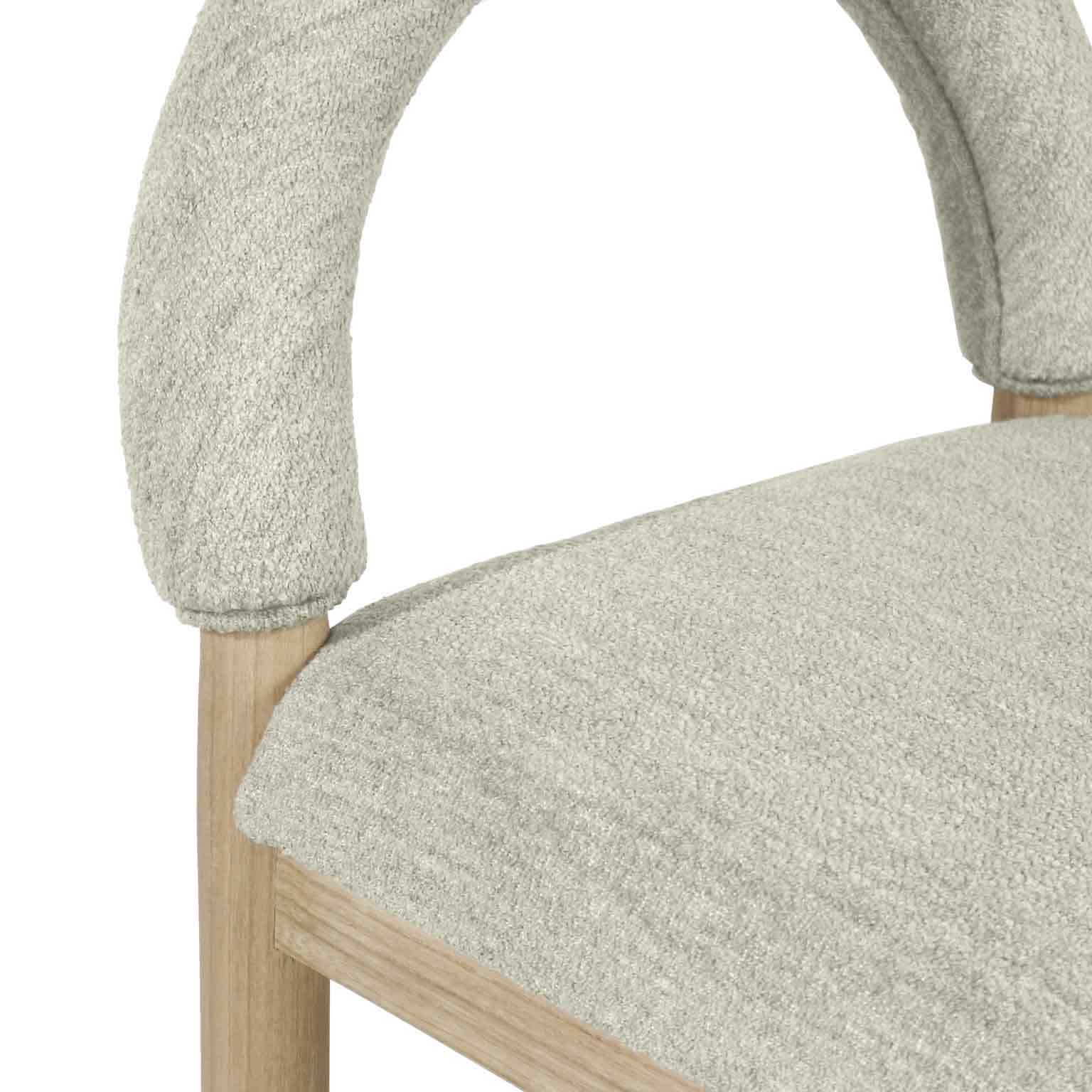 Close-up of a beige bouclé upholstered seat and curved arched back showing textured boucle fabric and a natural oak leg and frame.