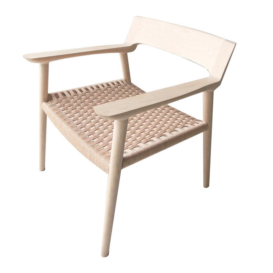 Scandinavian-style solid wood dining chair in a light natural finish with angled arms, low open back, tapered legs and a rope-woven seat for textured support.