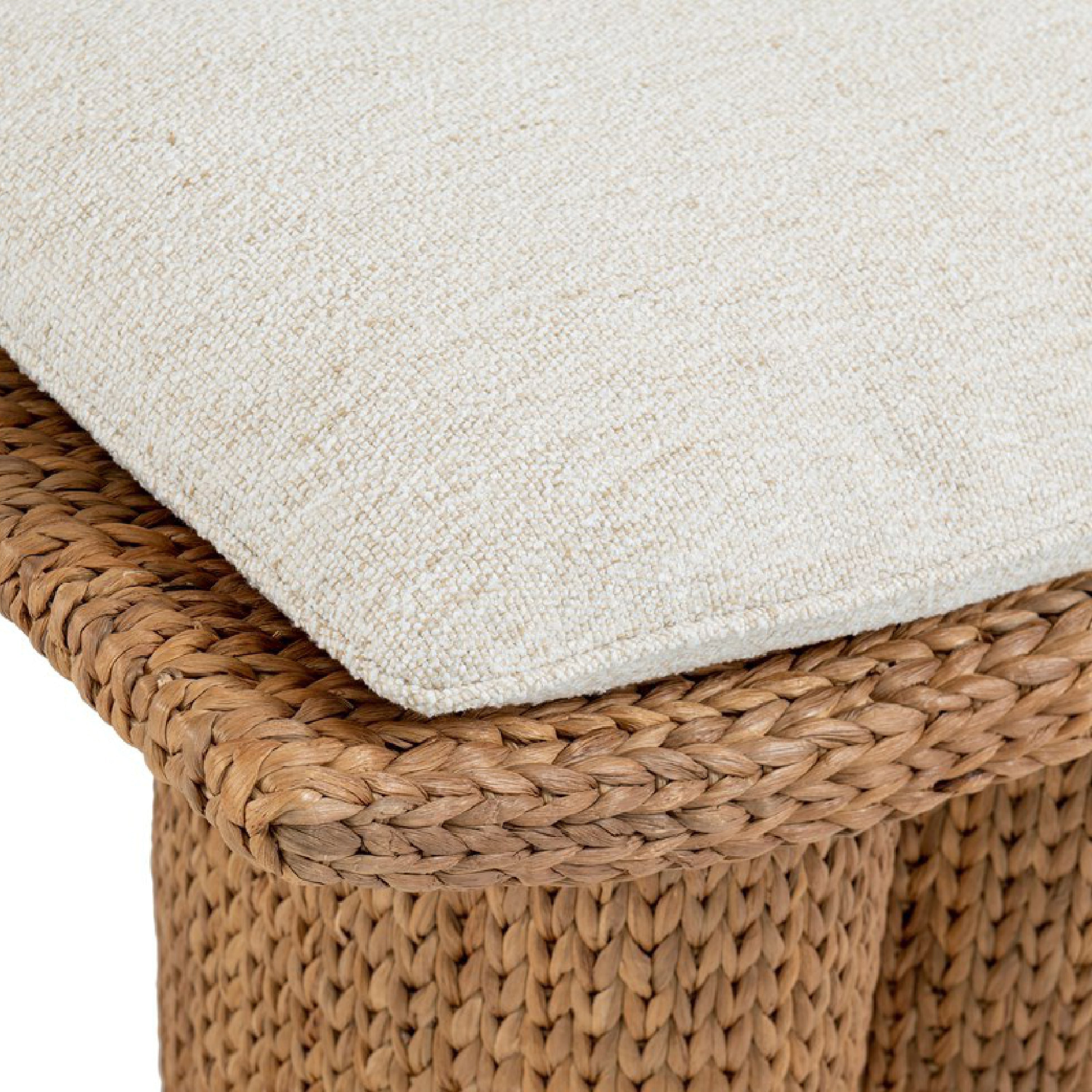 Close-up of a natural water hyacinth handwoven stool topped with a beige textured fabric cushion, showing the braided edge and woven detailing.