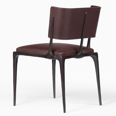 Rear three-quarter view of a modern dining chair upholstered in dark brown leather with a curved padded backrest, cushioned seat and slender sculpted dark metal legs.