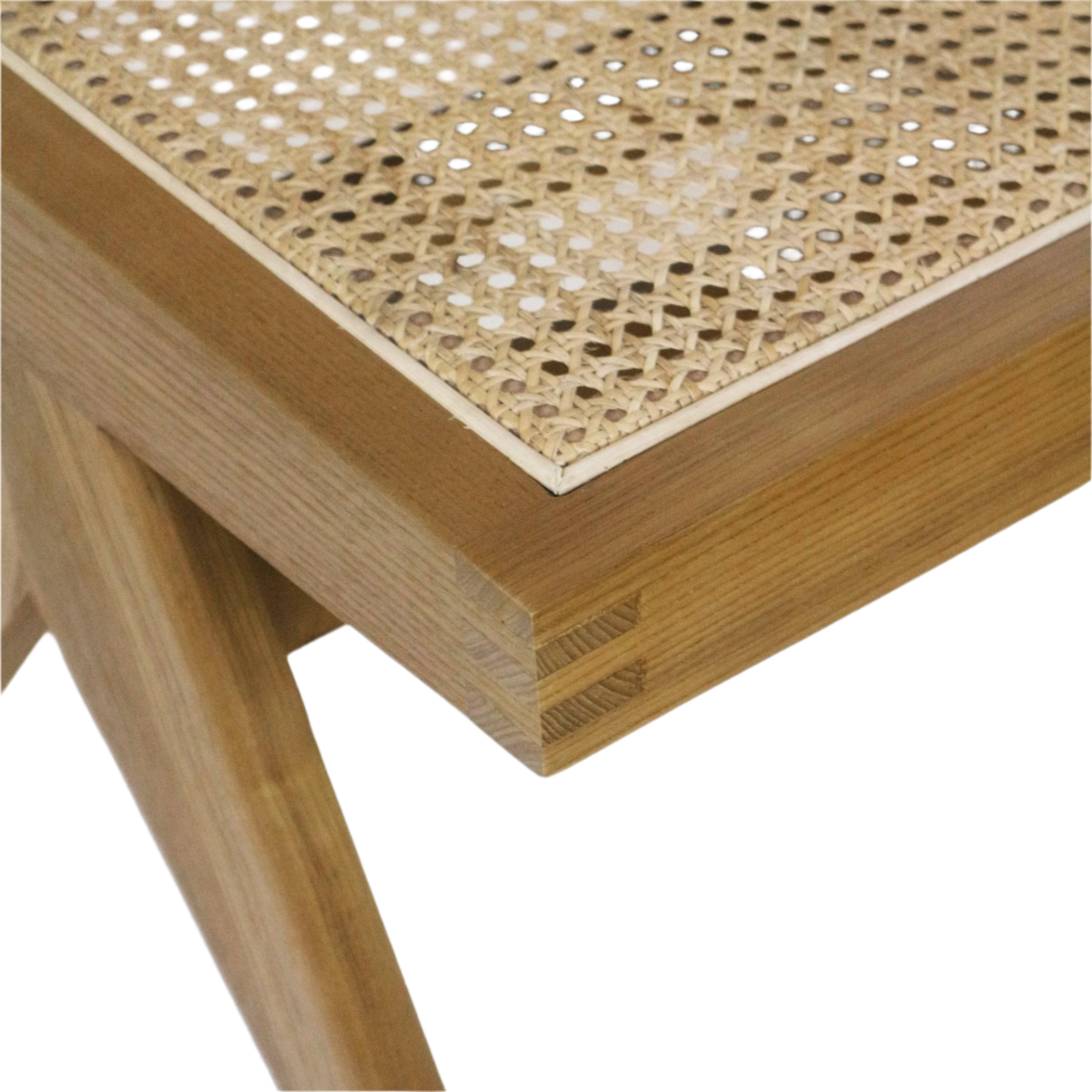 Close-up of a natural wood dining chair corner showing a woven cane seat, light blonde finish, visible corner joinery and a tapered leg.