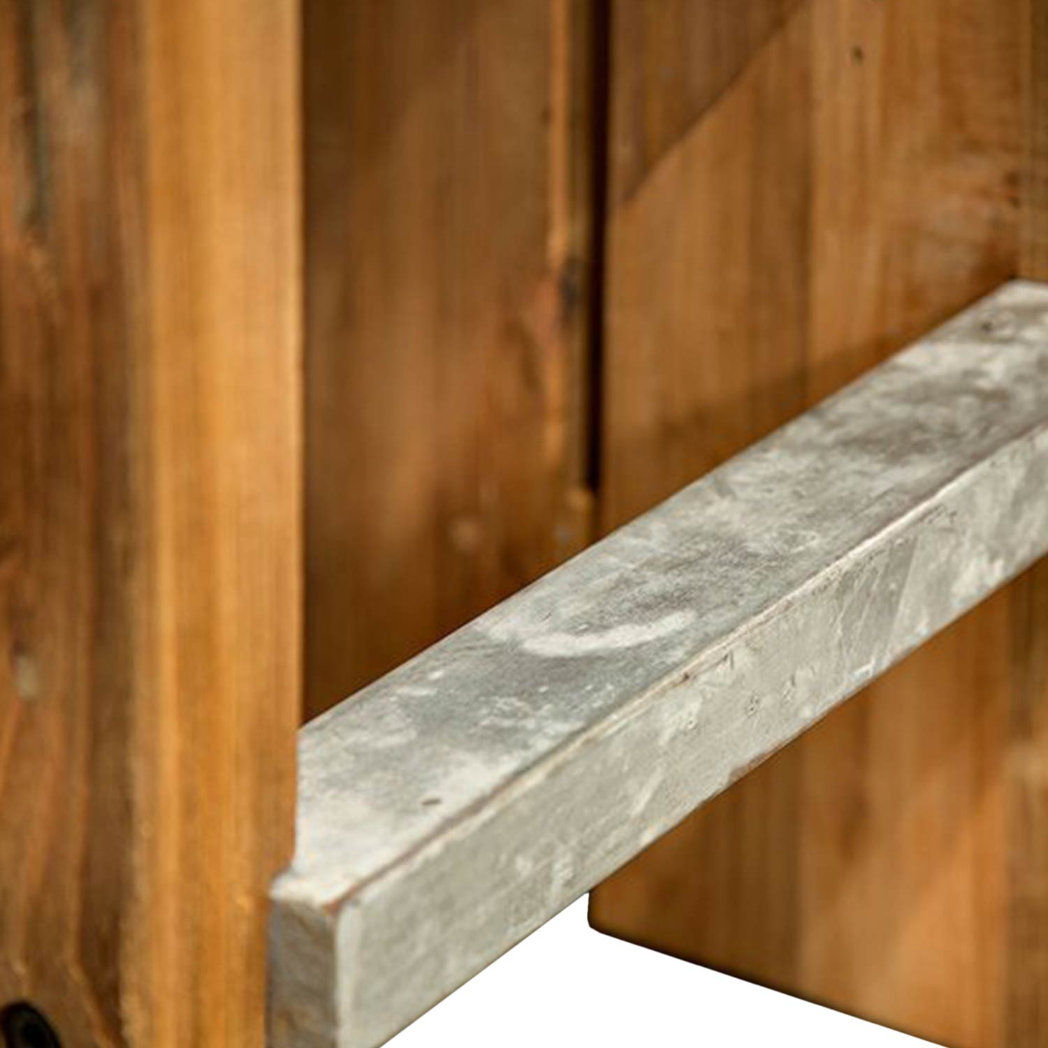 Close-up of a weathered gray metal square footrest mounted to natural teak slats on a backless outdoor bar stool, highlighting the galvanized texture and warm teak wood grain.