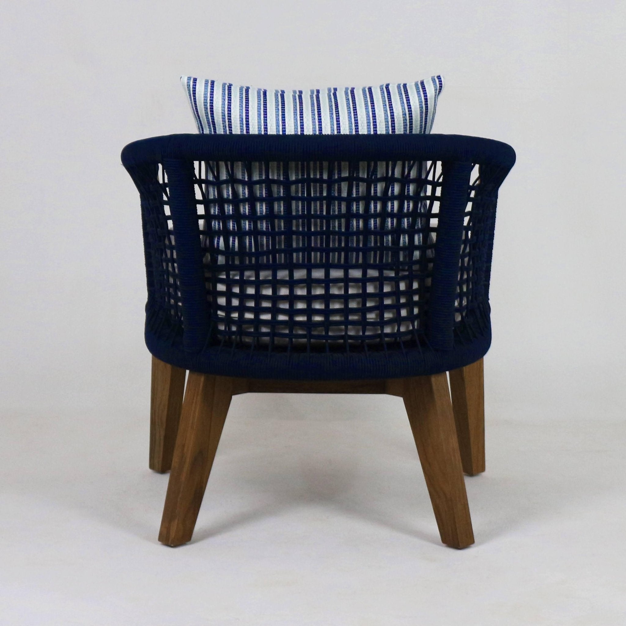 Rear view of a modern outdoor lounge chair with navy woven rope back, blue-and-white striped fabric cushion, and natural wood tapered legs.