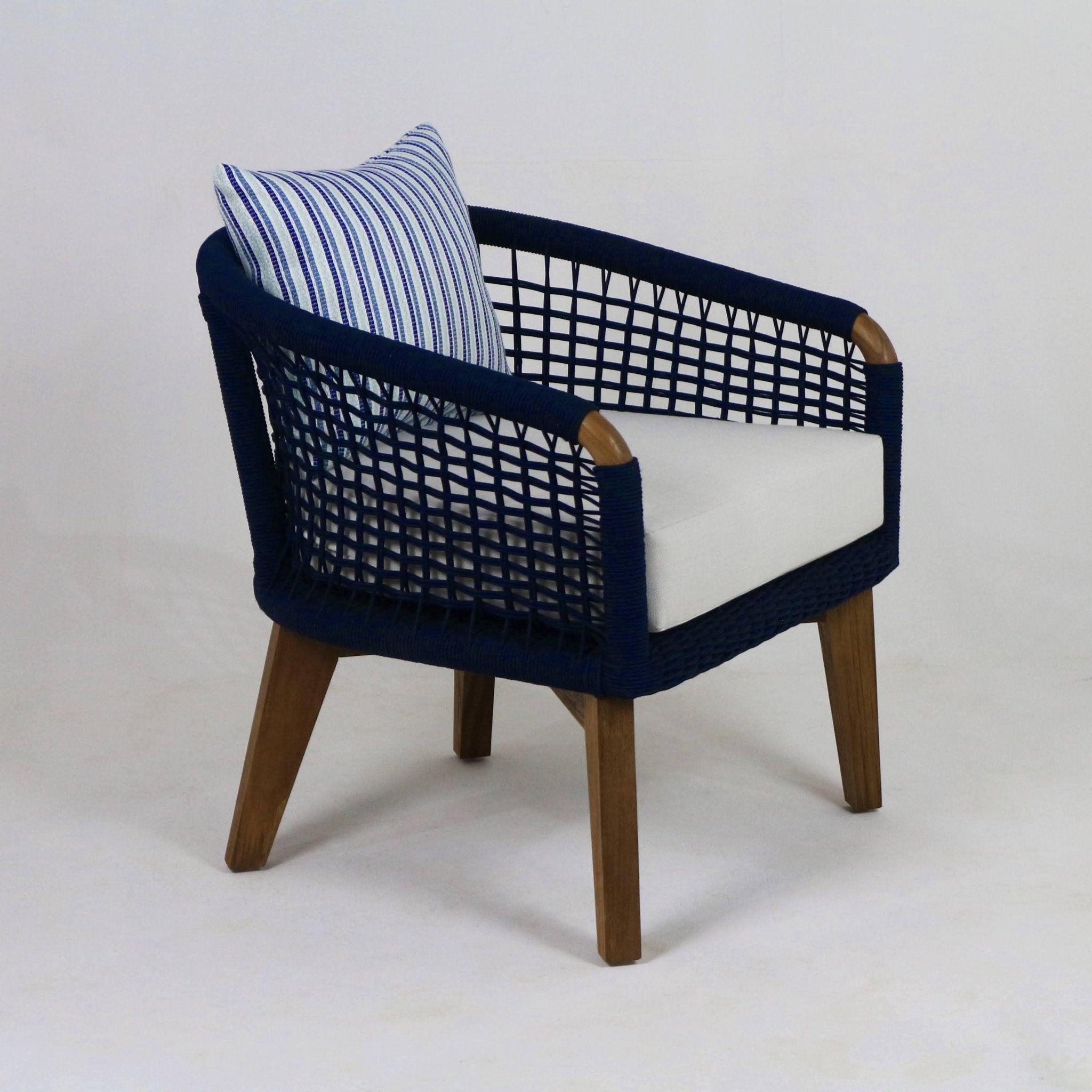 Contemporary outdoor lounge chair with navy rope-woven frame, natural wood legs, a white seat cushion and a blue-and-white striped throw pillow.