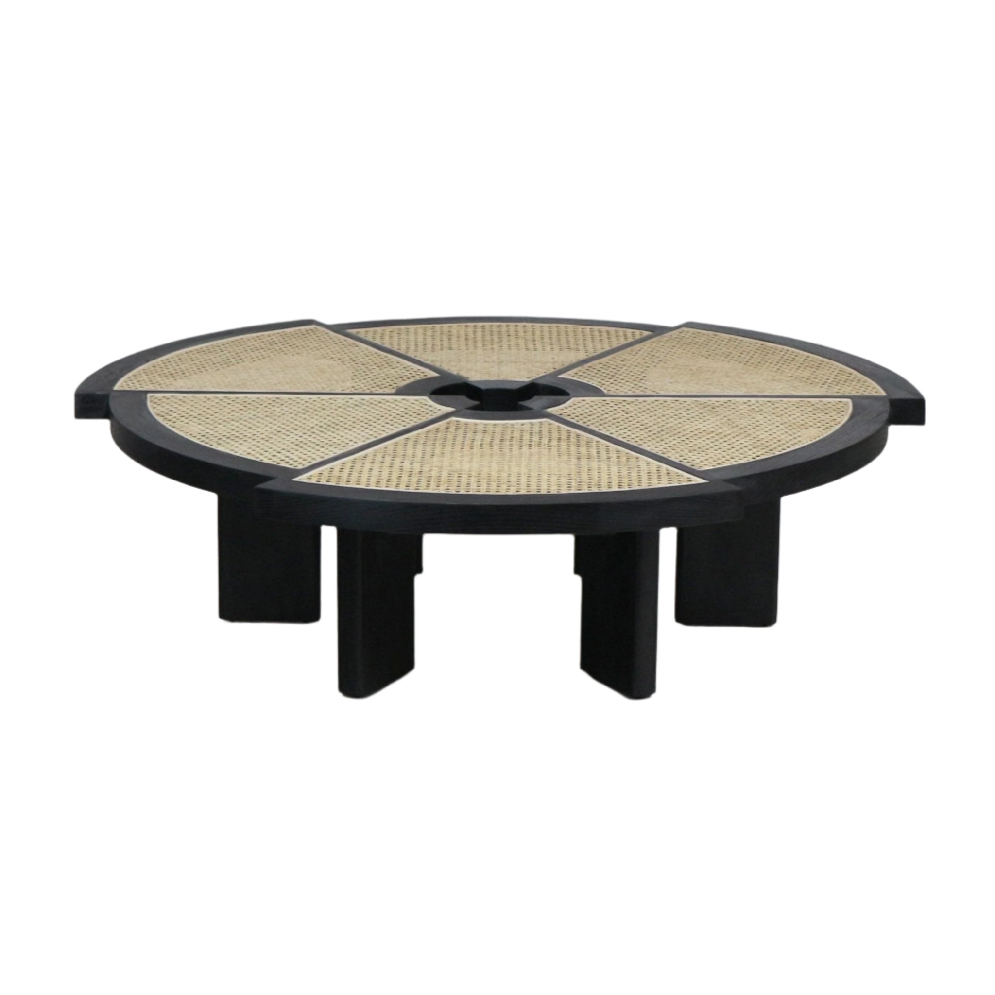 Low round coffee table with a black wood frame and six radial natural cane panels, a central circular opening, and chunky short black block legs in a modern midcentury-inspired style.