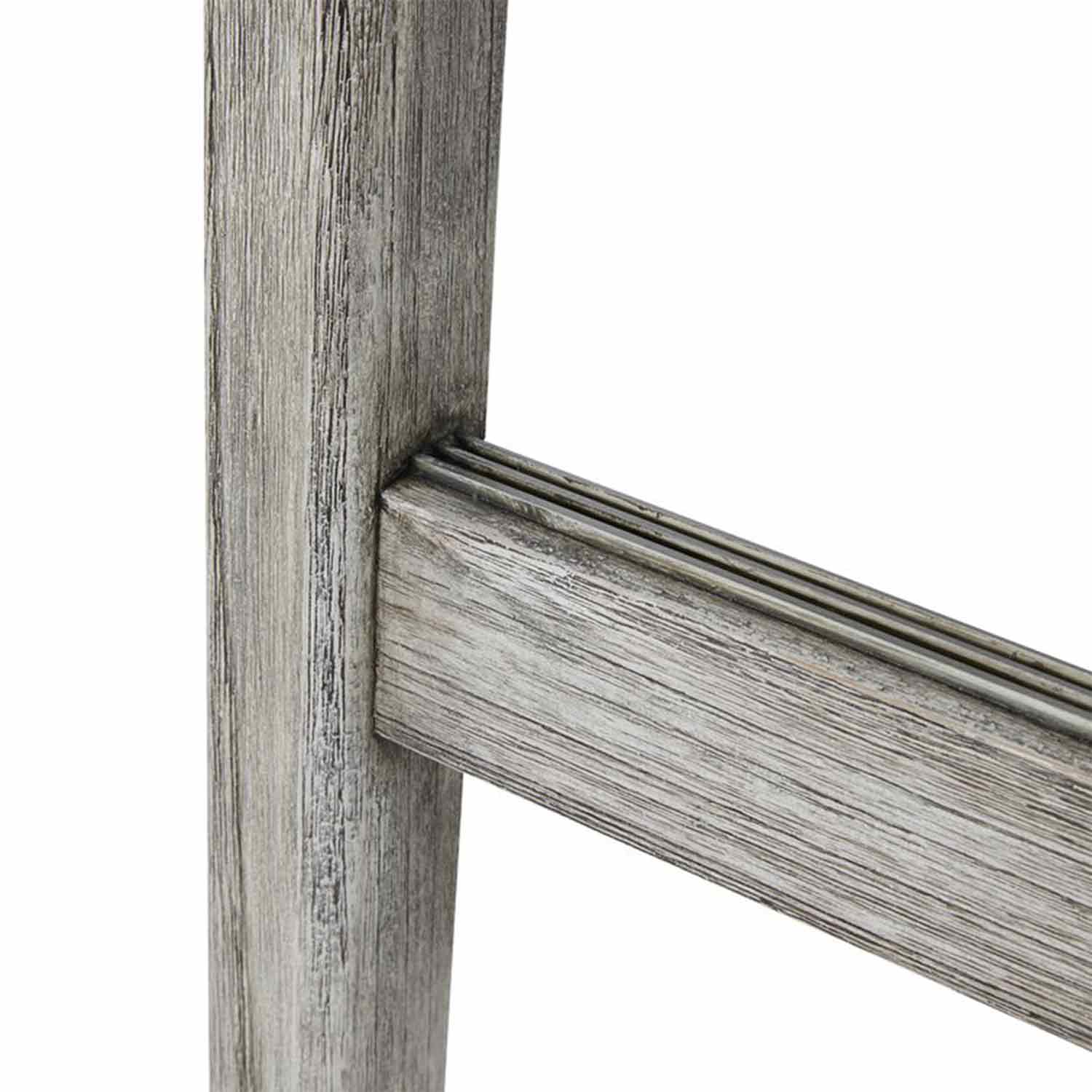 Close-up of a natural teak bar stool leg and horizontal stretcher showing weathered wood grain and three narrow grooves along the stretcher's top edge.