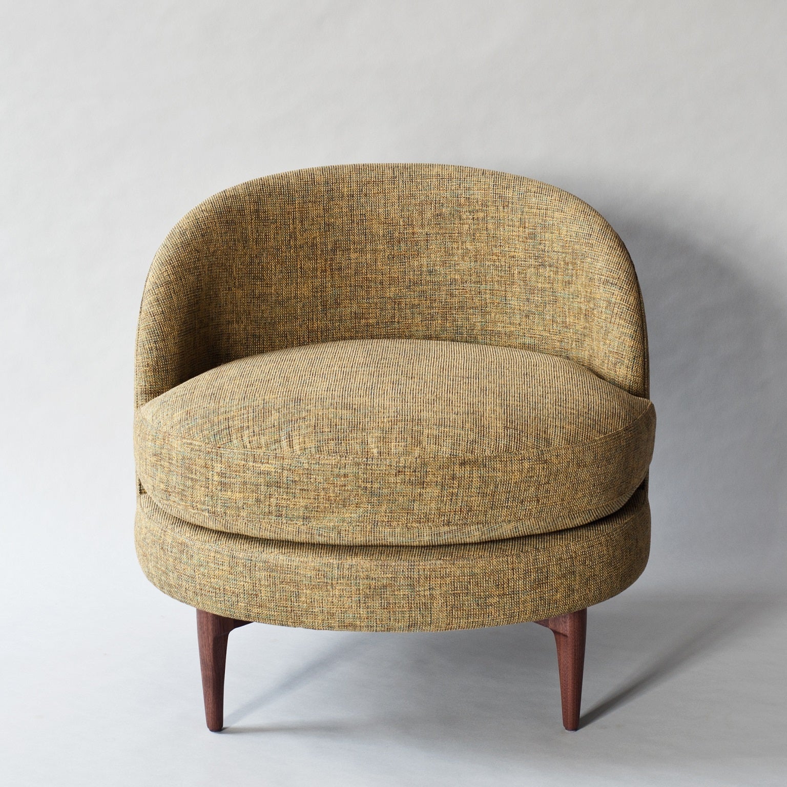 Modern accent chair with a rounded barrel back and deep cushioned seat upholstered in textured mustard-green boucle fabric, supported by tapered solid wood legs.