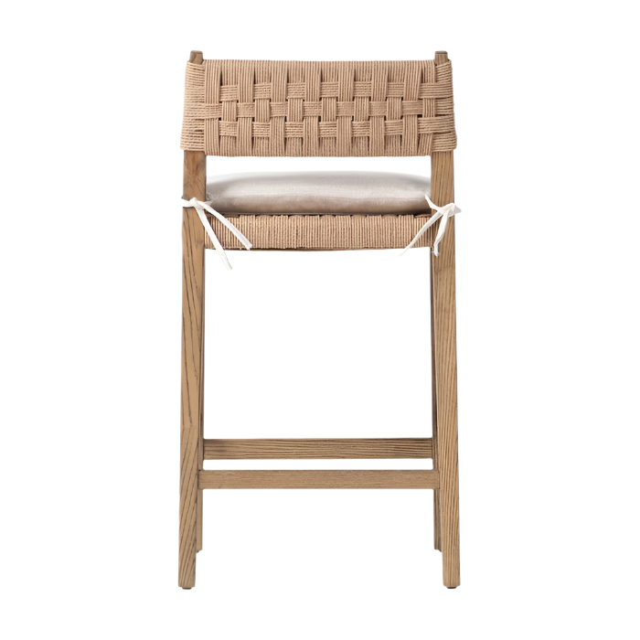 Modern oak counter stool with a woven natural papercord back and seat trim, light beige seat cushion tied with white straps, and a solid oak frame with a footrest.