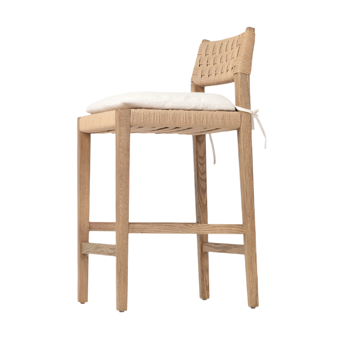 Side view of a modern oak counter stool with woven natural papercord back and seat, light oak finish, and a removable white tie-on seat cushion.