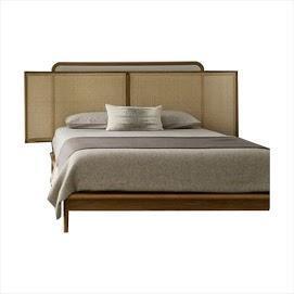 Scandinavian teak platform bed with a three-panel rattan cane headboard, low wooden base and neutral beige bedding with a single accent pillow.