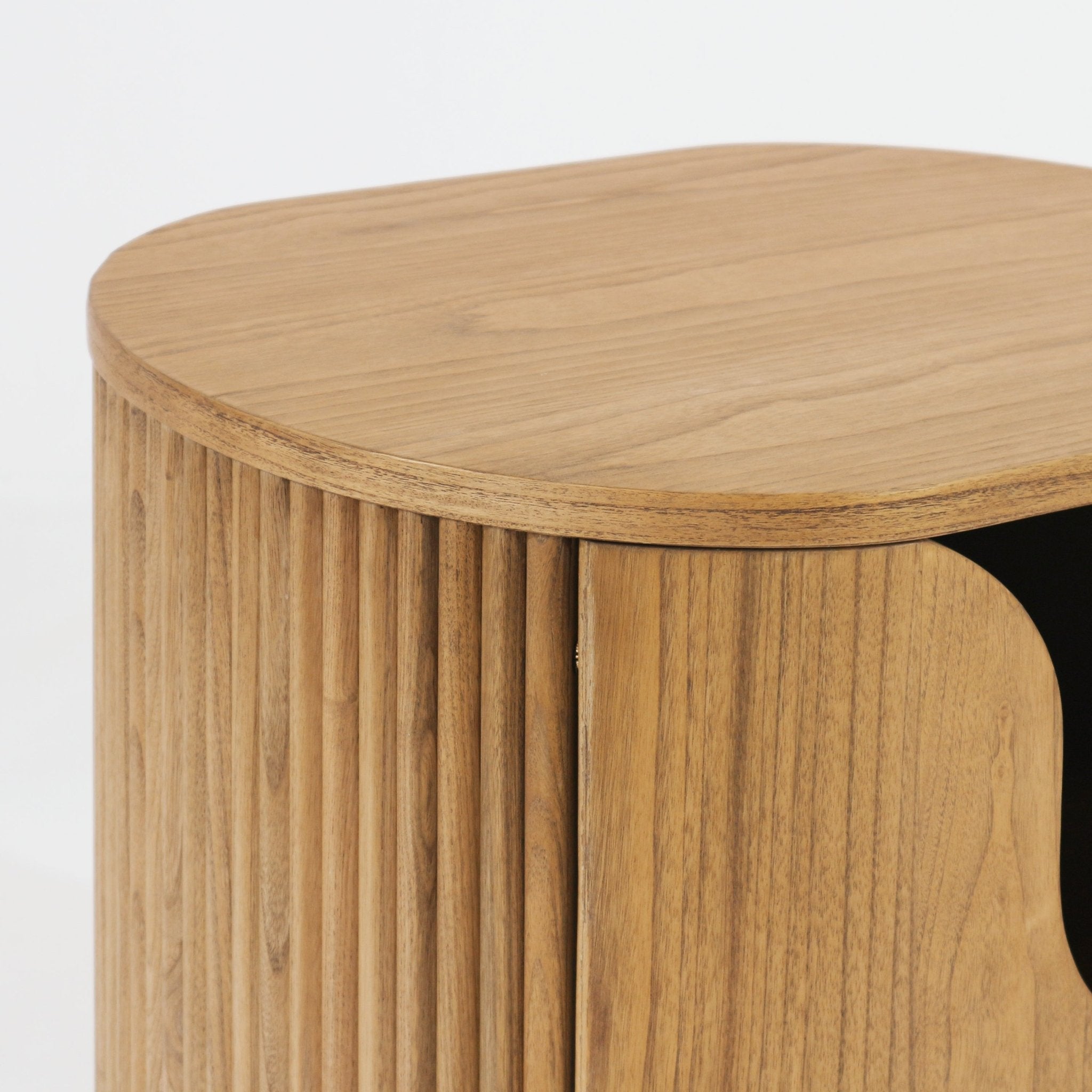 Close-up of a natural solid wood nightstand showing the rounded top edge and curved fluted front with vertical wood slats and a dark recessed interior in a light natural finish.